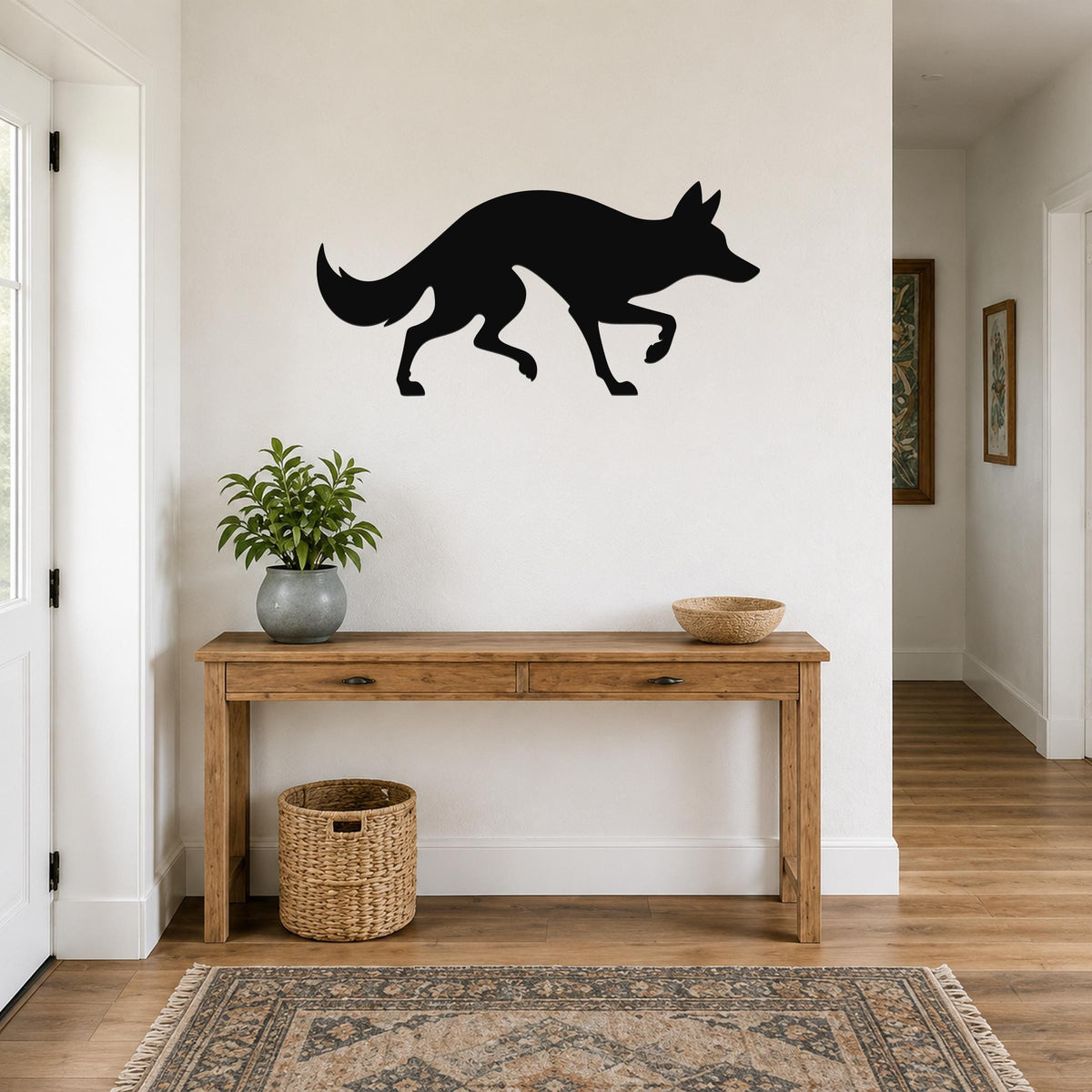 Black metal coyote wall art silhouette mounted above a wooden console table in a hallway.