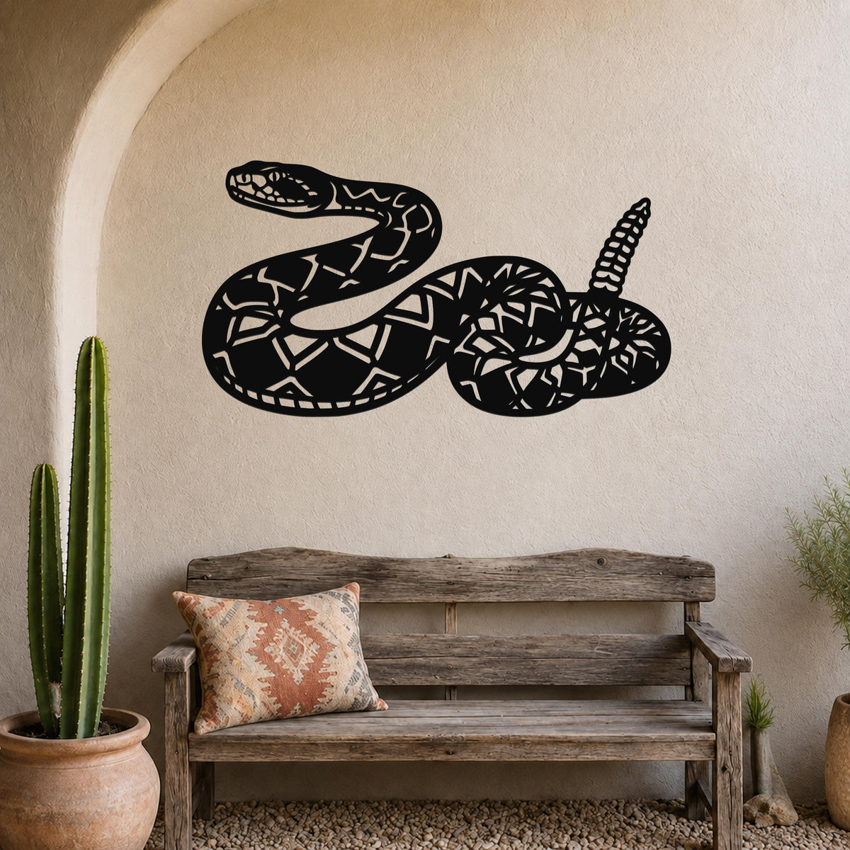 Black metal wall art sculpture of a coiled rattlesnake with intricate internal cutouts, mounted on a beige stucco wall above a rustic wooden bench in a desert-themed entryway.
