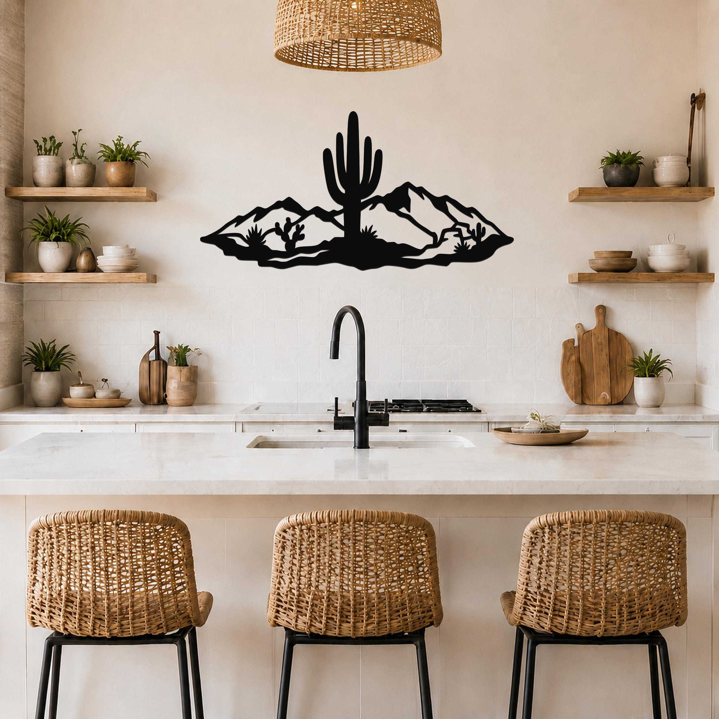 Black metal wall art silhouette of a saguaro cactus and mountains, mounted above a kitchen counter with wicker bar stools.