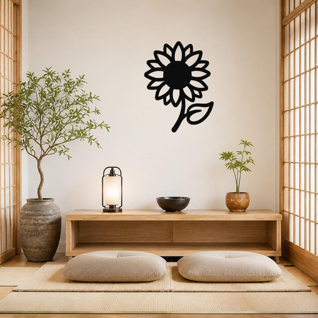 Black metal sunflower wall art with a bold silhouette and leaf detail, mounted on a wall above a wooden console in a minimalist room.
