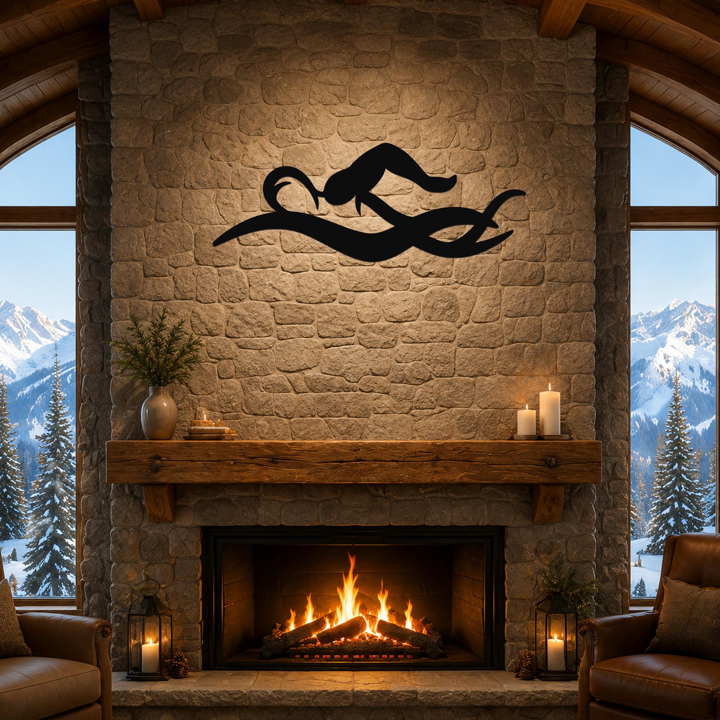 Black metal swimmer wall art with fluid motion cutouts, mounted above a stone fireplace in a rustic living room.