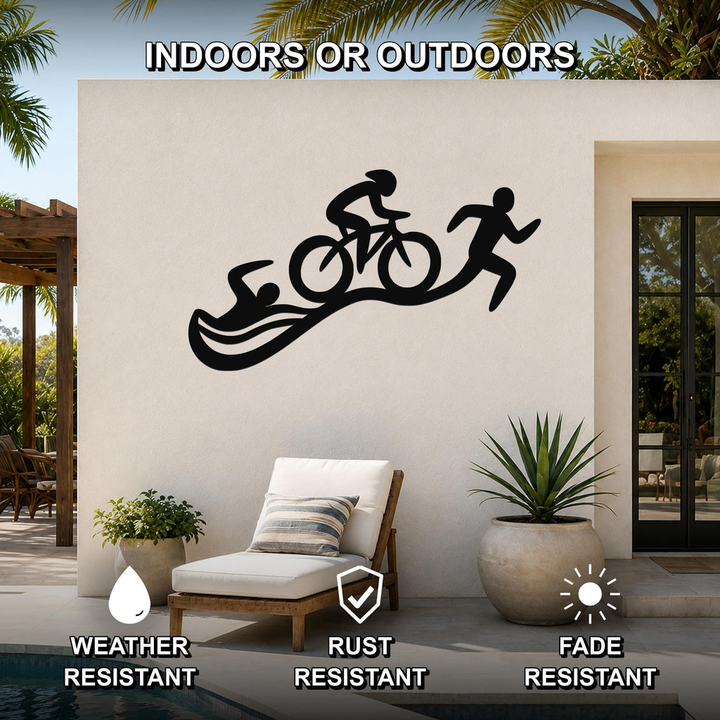 Black metal triathlon wall art with swim, bike, and run silhouettes, mounted on an outdoor patio wall above a lounge chair.