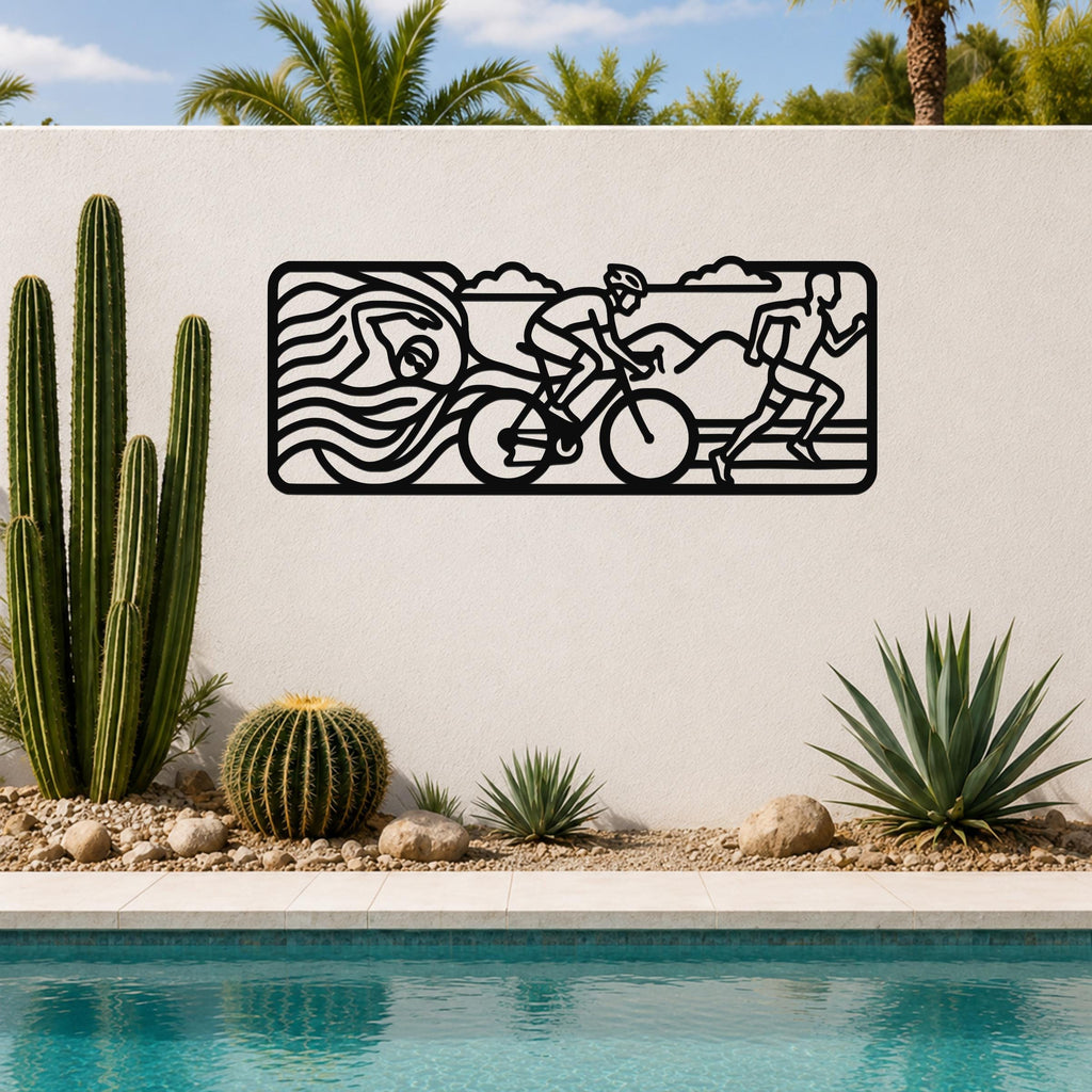 Black metal triathlon wall art with swim, bike, and run silhouettes, mounted on an outdoor wall above a pool with cacti and palm trees.