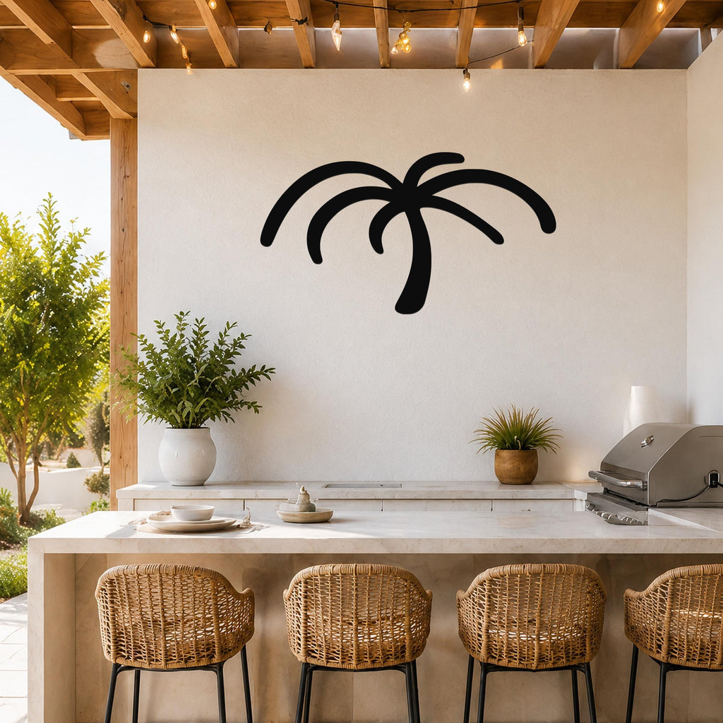 Black metal palm tree wall art with curved frond cutouts, mounted on a white wall above a kitchen counter in a covered outdoor patio.