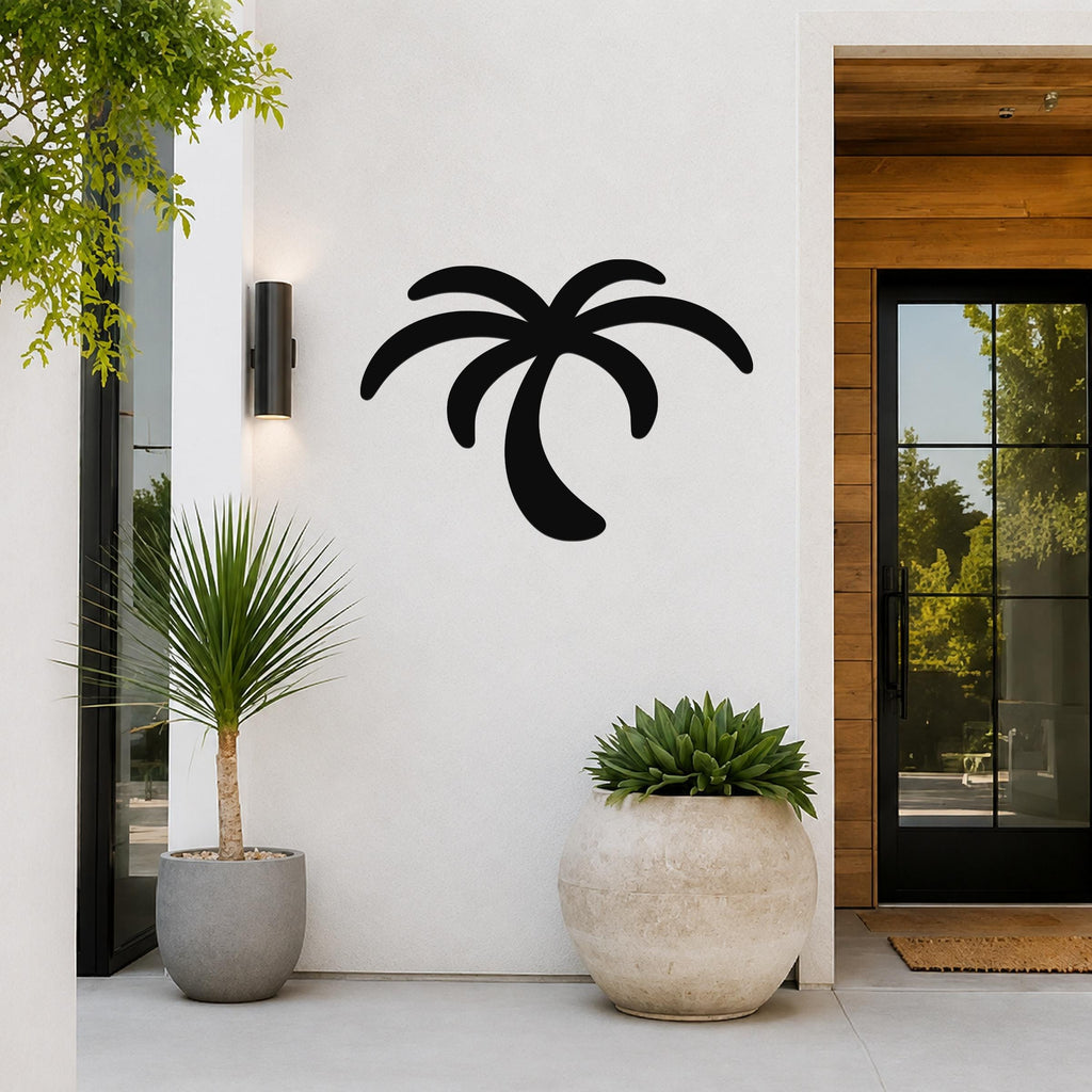 Black metal palm tree wall art silhouette mounted on a white exterior wall beside a glass door and potted plants.