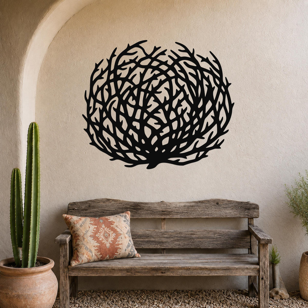 Black metal tumbleweed wall art with intricate branch cutouts, mounted on a textured beige wall above a rustic wooden bench in a southwestern-style entryway.