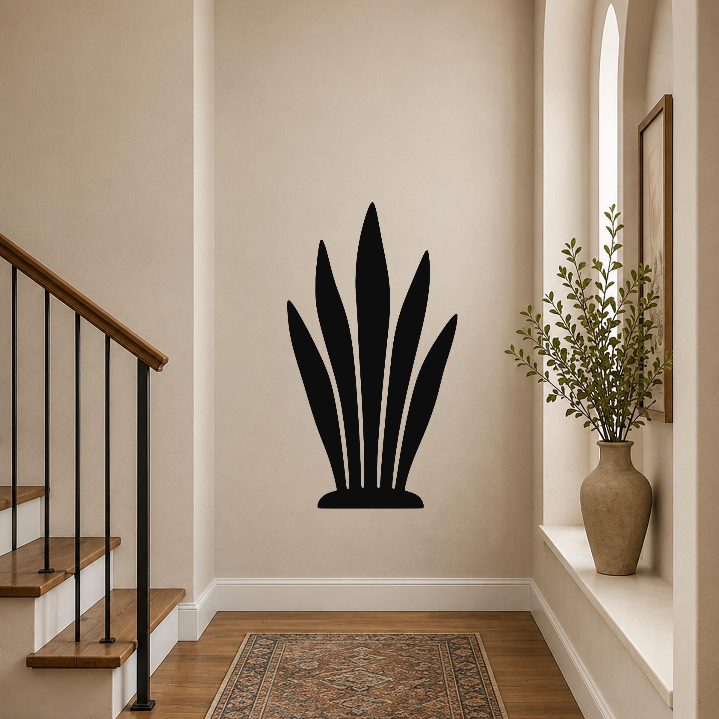 Black metal snake plant wall art with leaf cutouts, mounted on a hallway wall above a patterned rug.