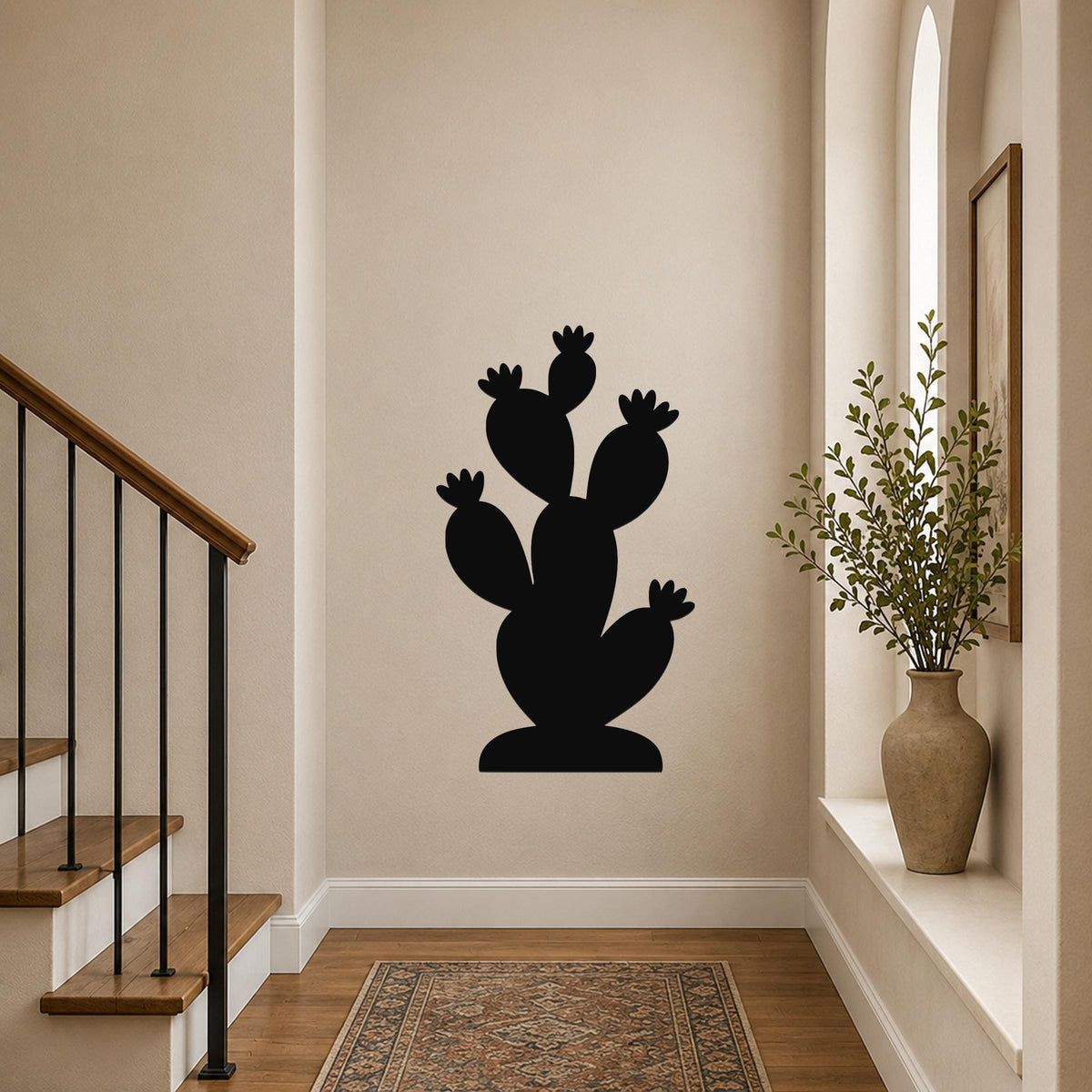 Black metal prickly pear cactus wall art with multiple pads and flower cutouts, mounted on a hallway wall above a patterned rug.
