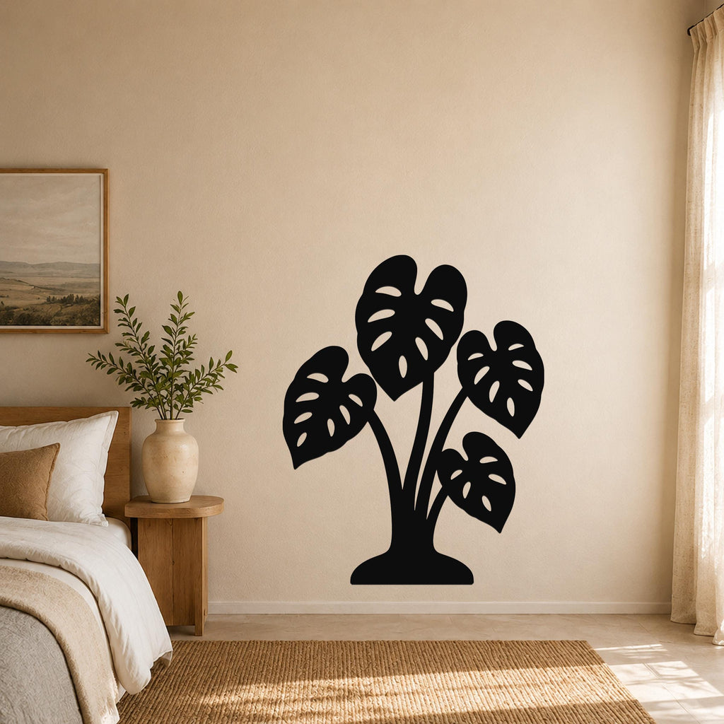 Black metal wall art silhouette of a monstera plant with leaf cutouts, mounted on a bedroom wall above a woven rug.