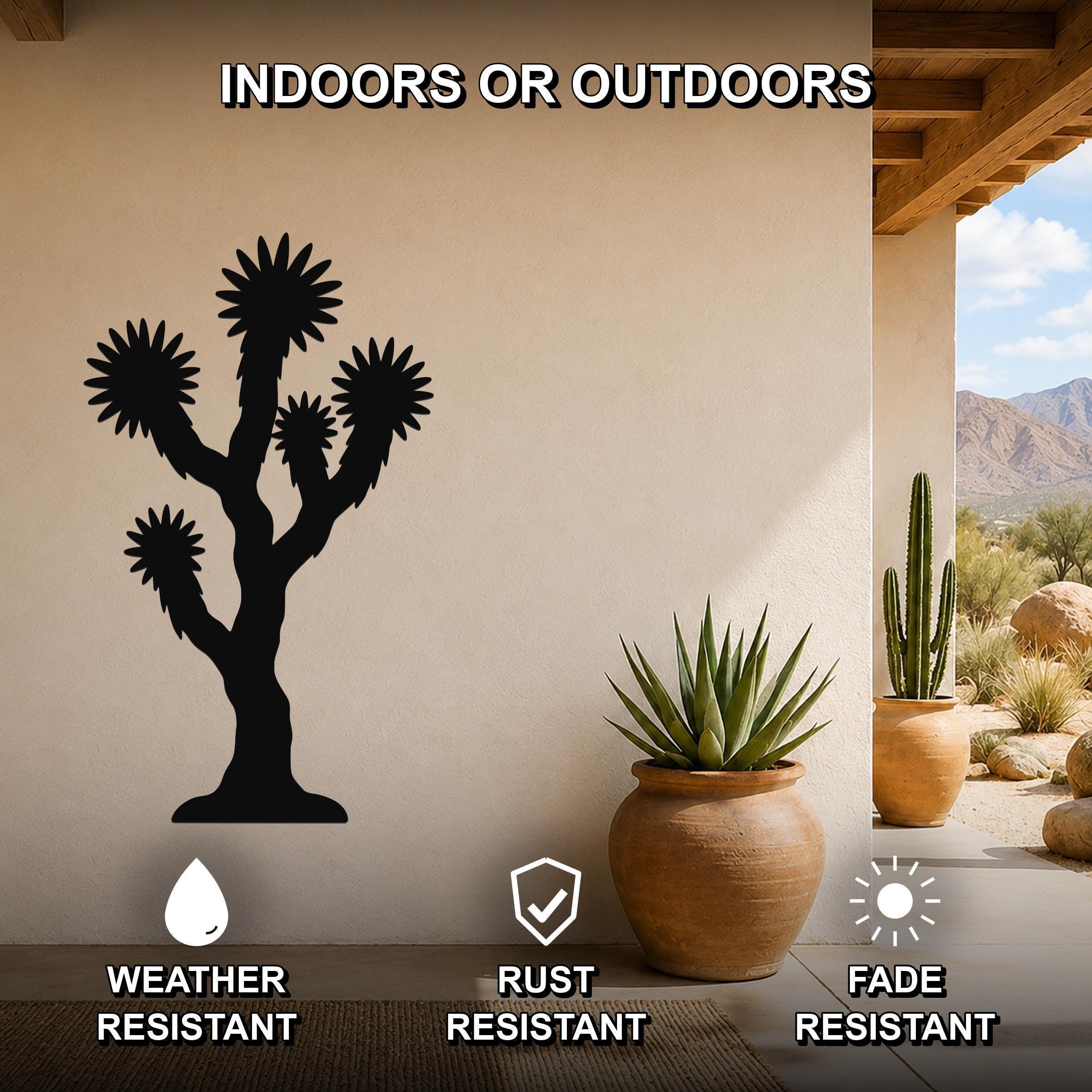 Black metal Joshua tree wall art silhouette mounted on a beige outdoor wall, displayed above a potted succulent on a patio with desert scenery visible through an opening.