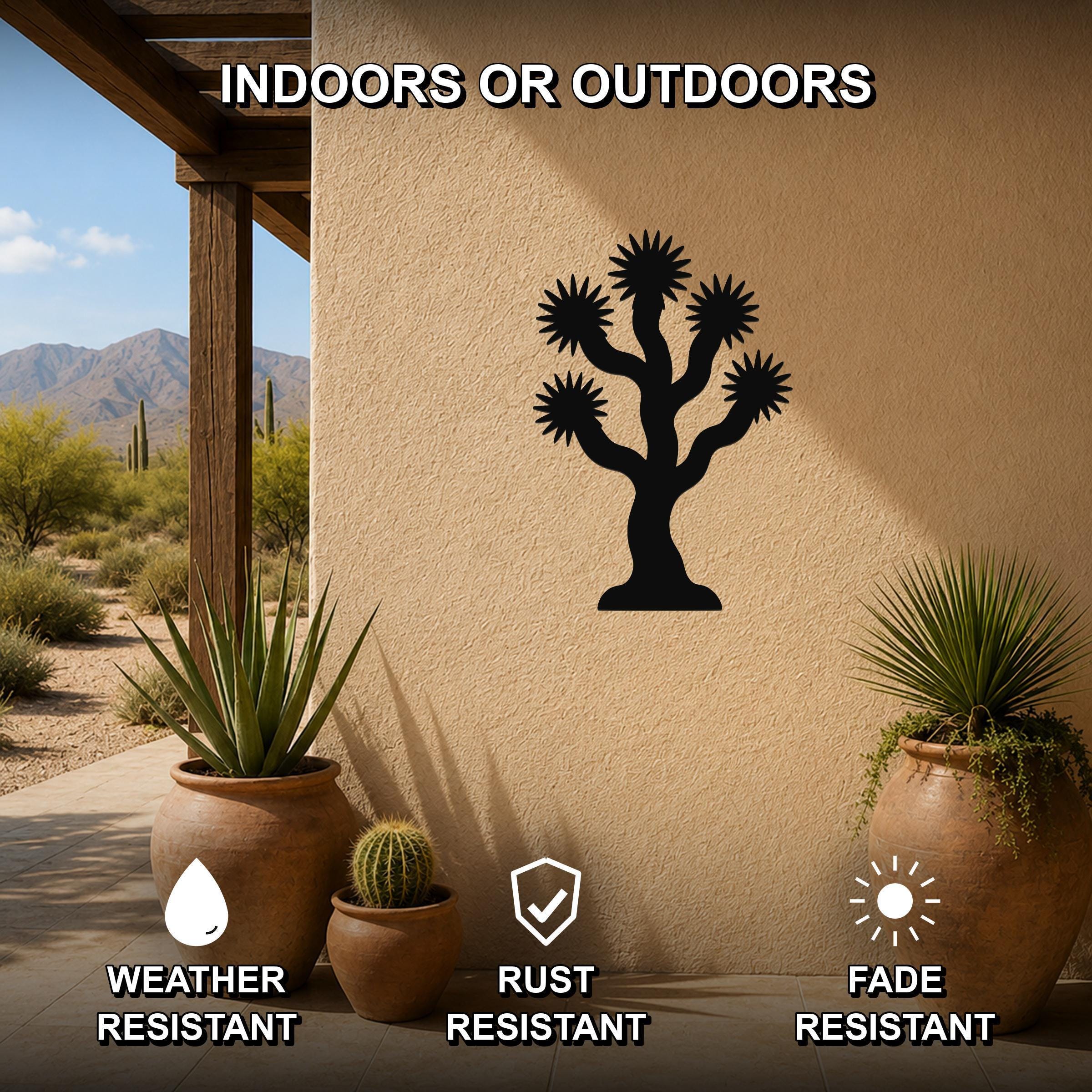 Black metal Joshua tree wall art with starburst cutouts, mounted on a stucco outdoor wall above potted plants on a patio.