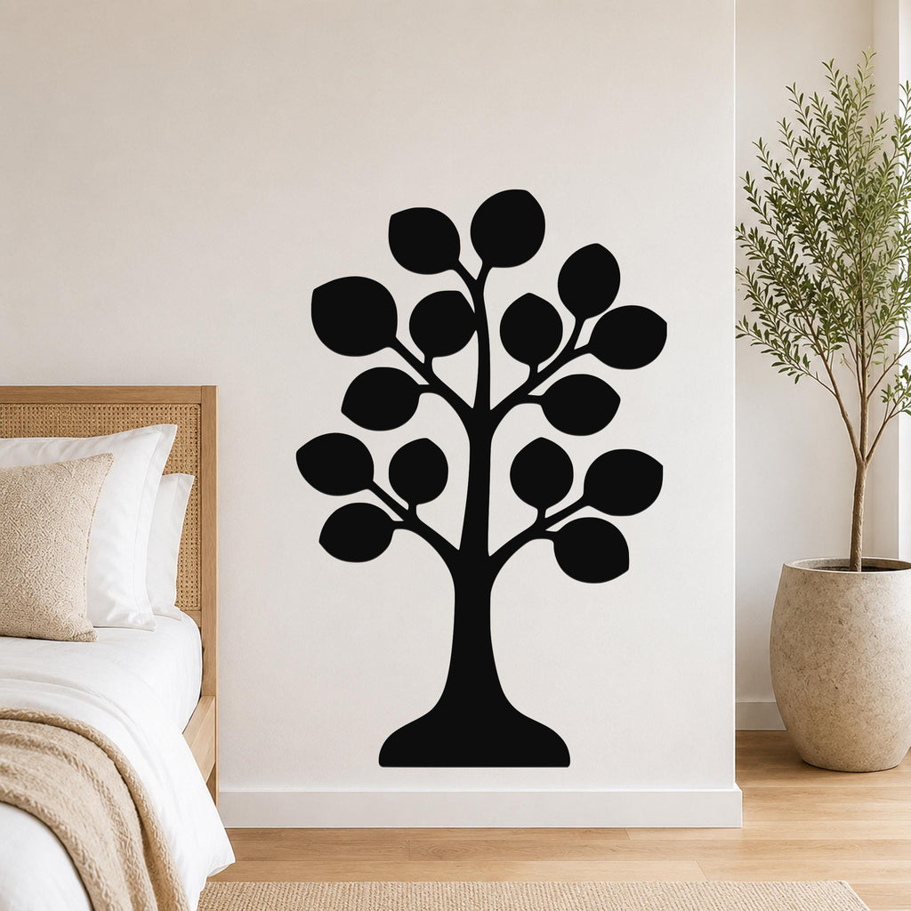 Black metal tree wall art with leaf cutouts, mounted on a bedroom wall above a bed.