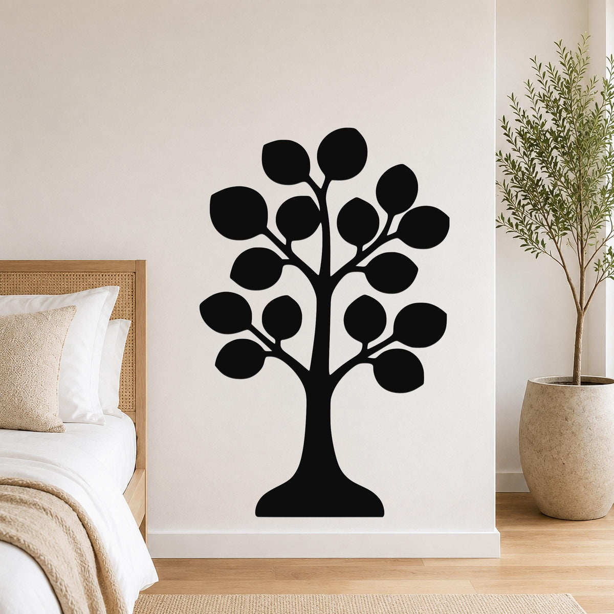 Black metal tree wall art with leaf cutouts, mounted on a bedroom wall above a bed.
