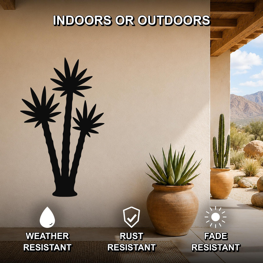 Black metal wall art featuring a silhouette of three desert plants, mounted on a beige outdoor wall beside potted succulents, suitable for indoor or outdoor use.