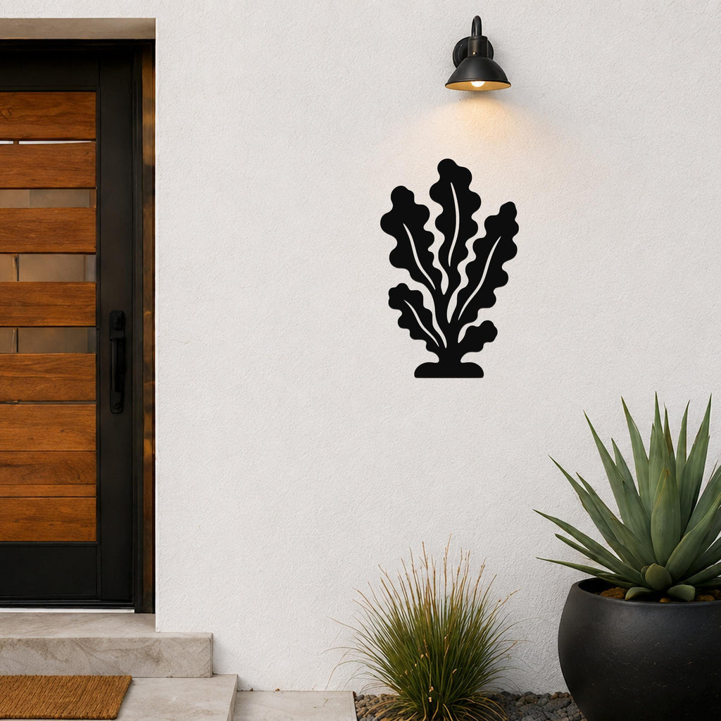 Black metal kelp wall art with leafy cutouts, mounted on an outdoor wall beside a front door and potted plants.