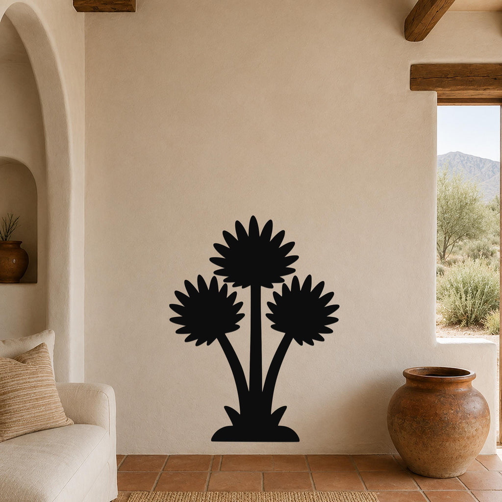 Black metal wall art featuring a silhouette of three desert wildflowers, mounted on a beige living room wall above a sofa.