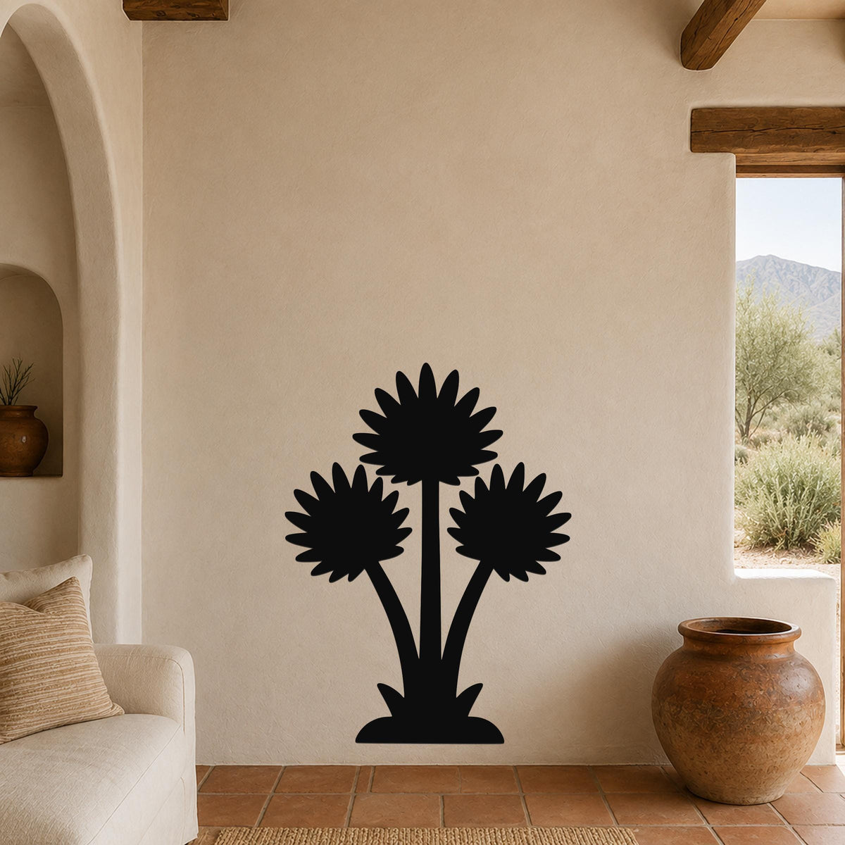 Black metal wall art featuring a silhouette of three desert wildflowers, mounted on a beige living room wall above a sofa.