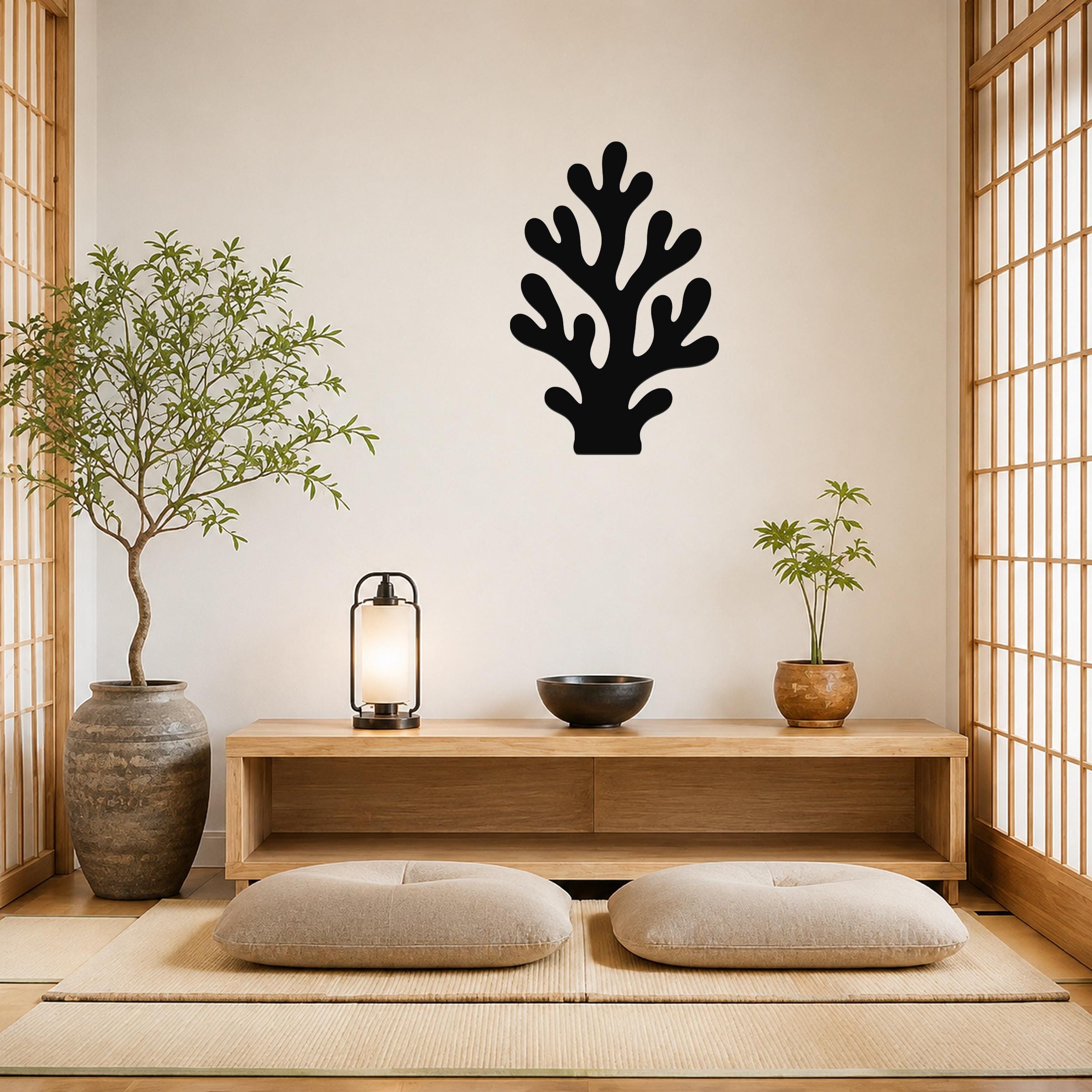 Black metal coral wall art with branching cutouts, mounted on a beige wall above a wooden console in a minimalist room.