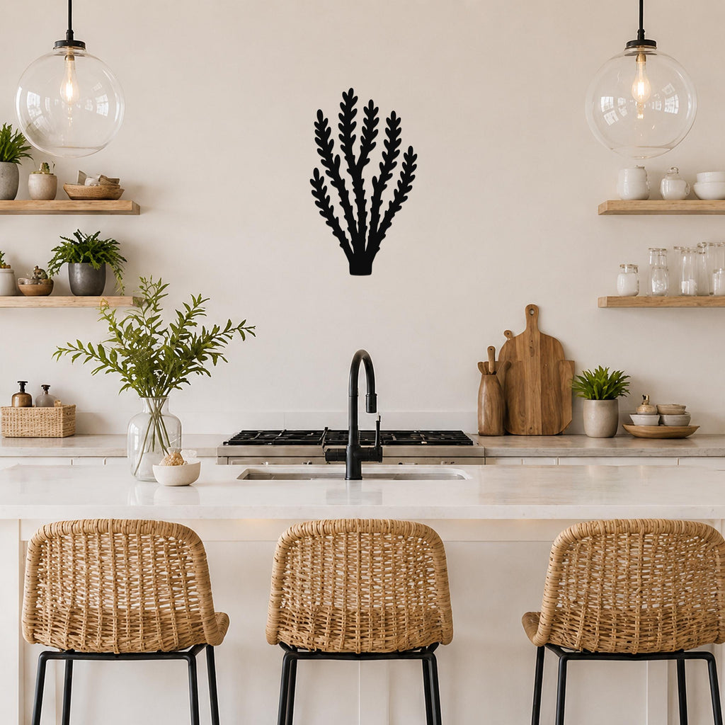 Black metal wall art in a desert branch silhouette, mounted on a kitchen wall above a counter with wicker stools and pendant lights.
