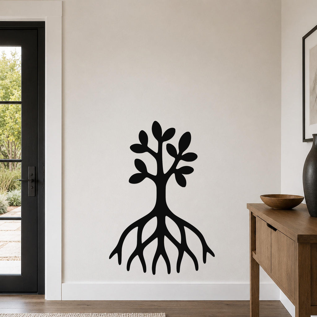 Black metal wall art in the shape of a tree with visible roots and leafy branches, mounted on a white wall in a living room.