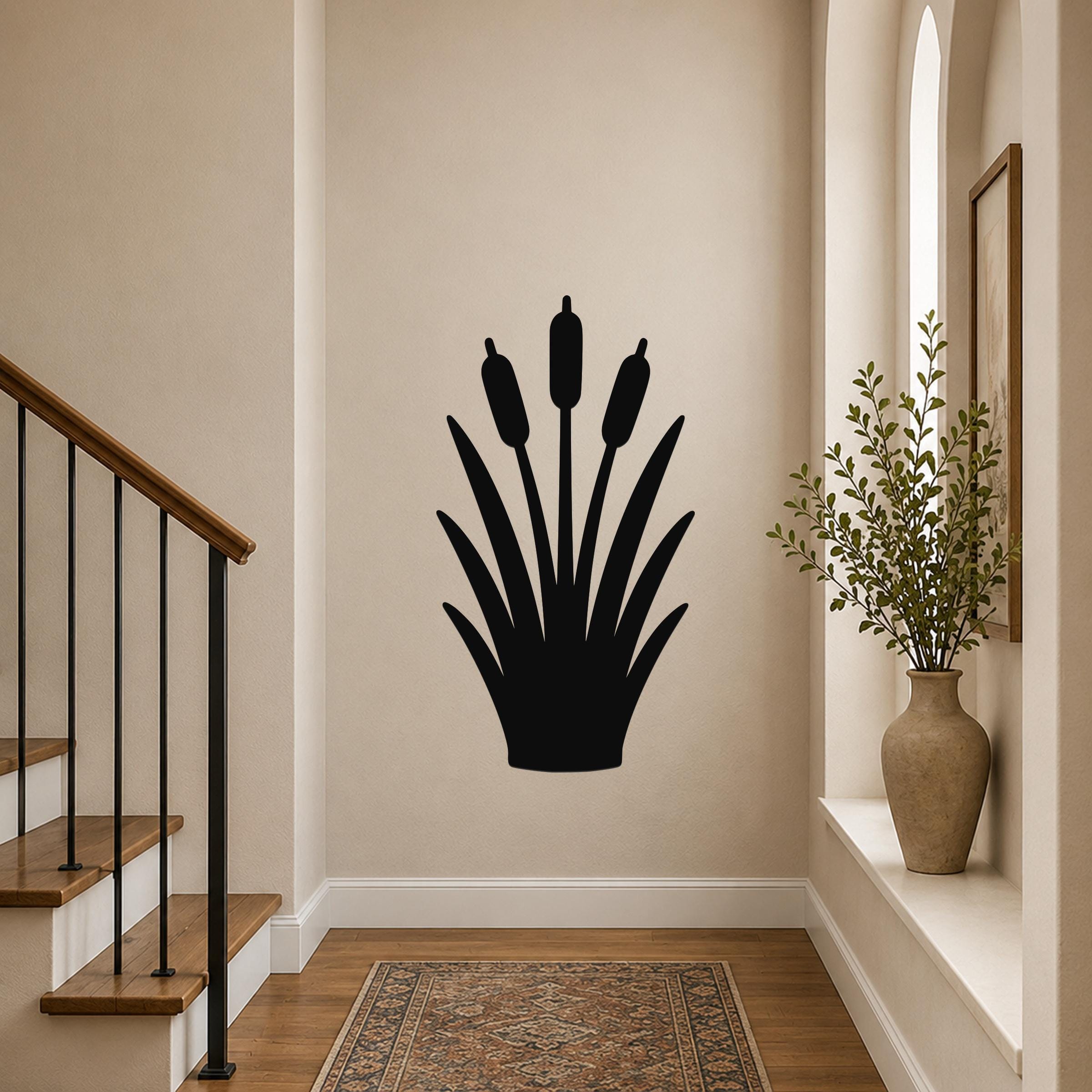 Black metal cattail wall art silhouette with three seed heads and leafy base, mounted on a hallway wall near a staircase and window.