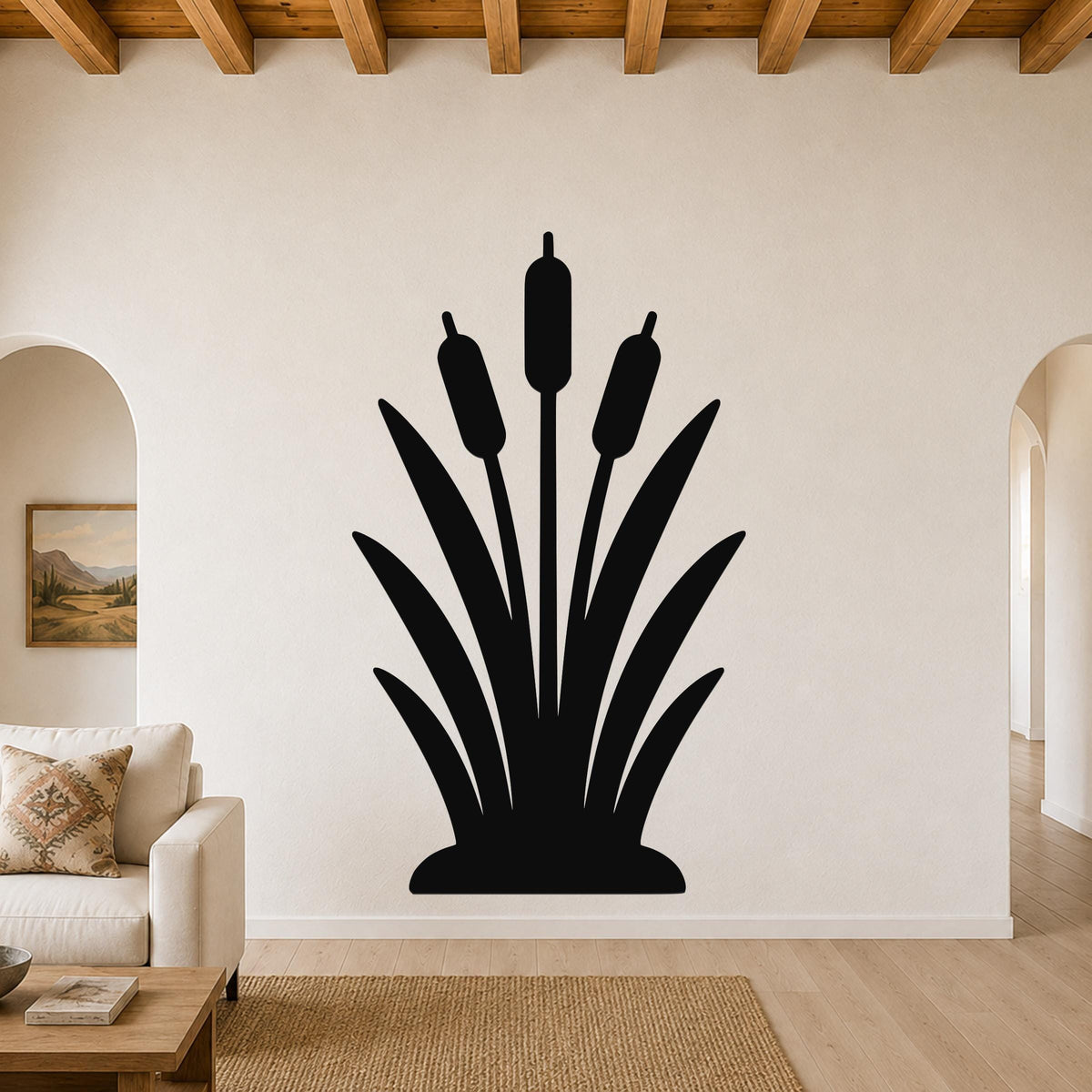 Black metal cattail wall art silhouette with three seed heads and long leaves, mounted on a living room wall above a sofa.