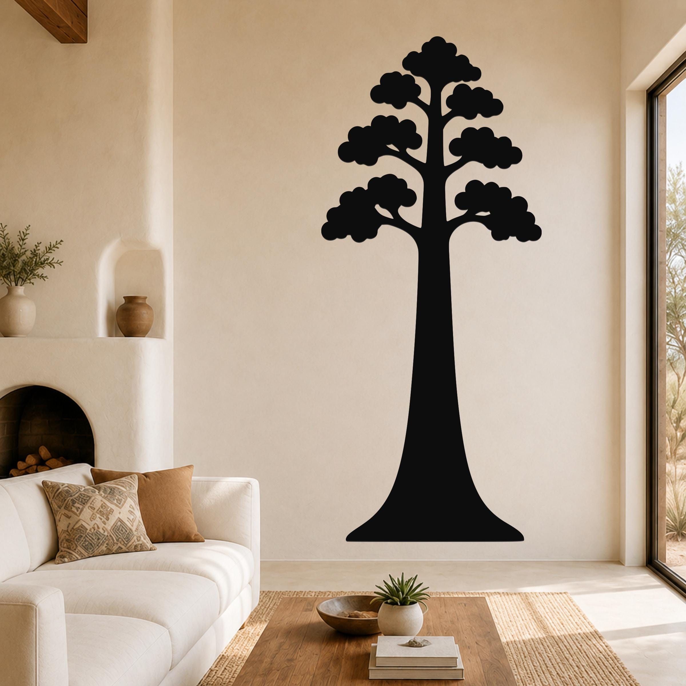 Black metal sequoia tree wall art with layered canopy cutouts, mounted on a living room wall above a white sofa.