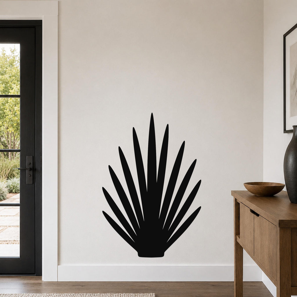 Black metal wall art in a fan-shaped silhouette of wild grass, mounted on a light-colored wall in a living room near a door and console table.