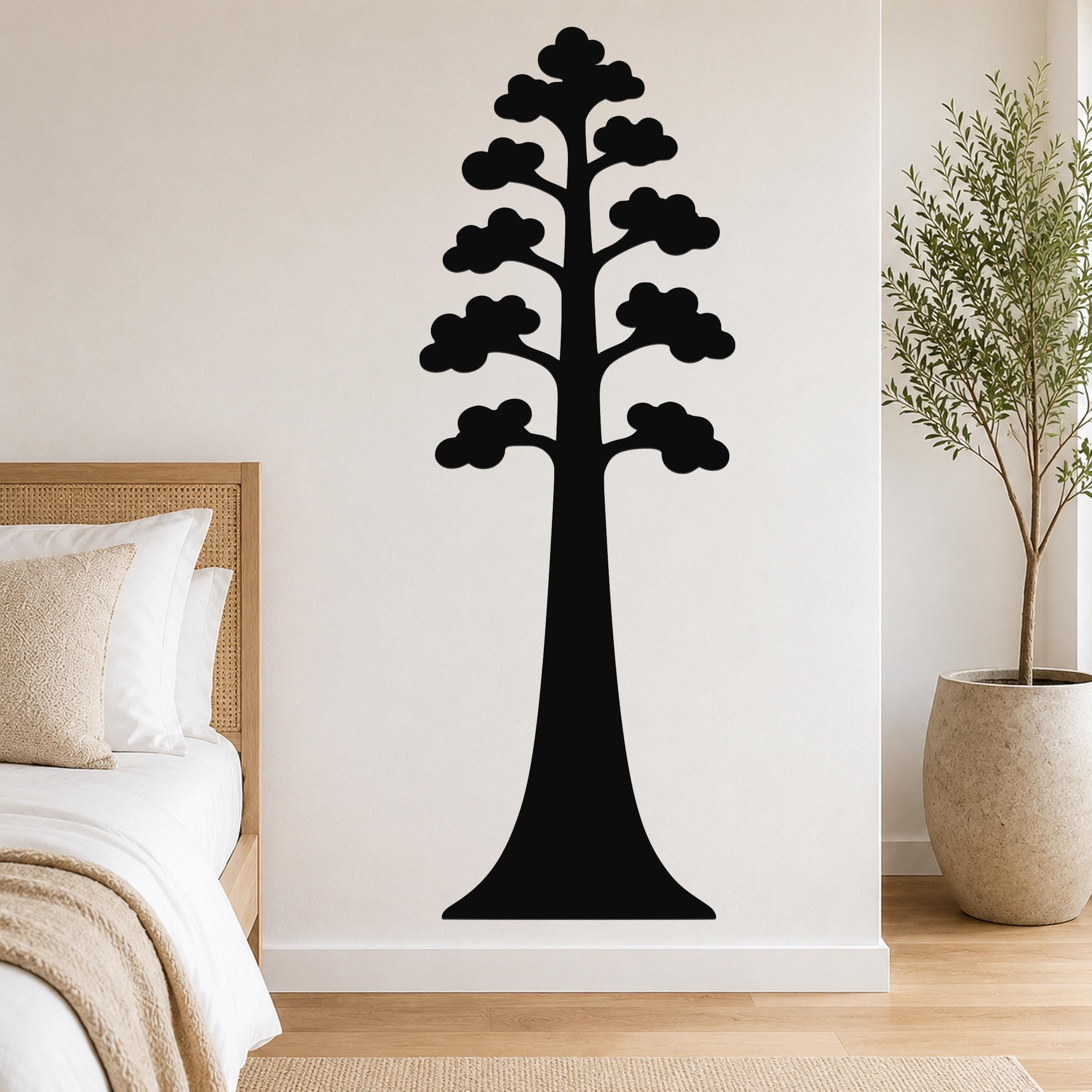 Black metal wall art in the silhouette of a sequoia tree with layered cloud-like branches, mounted on a white wall above a bed in a bedroom.