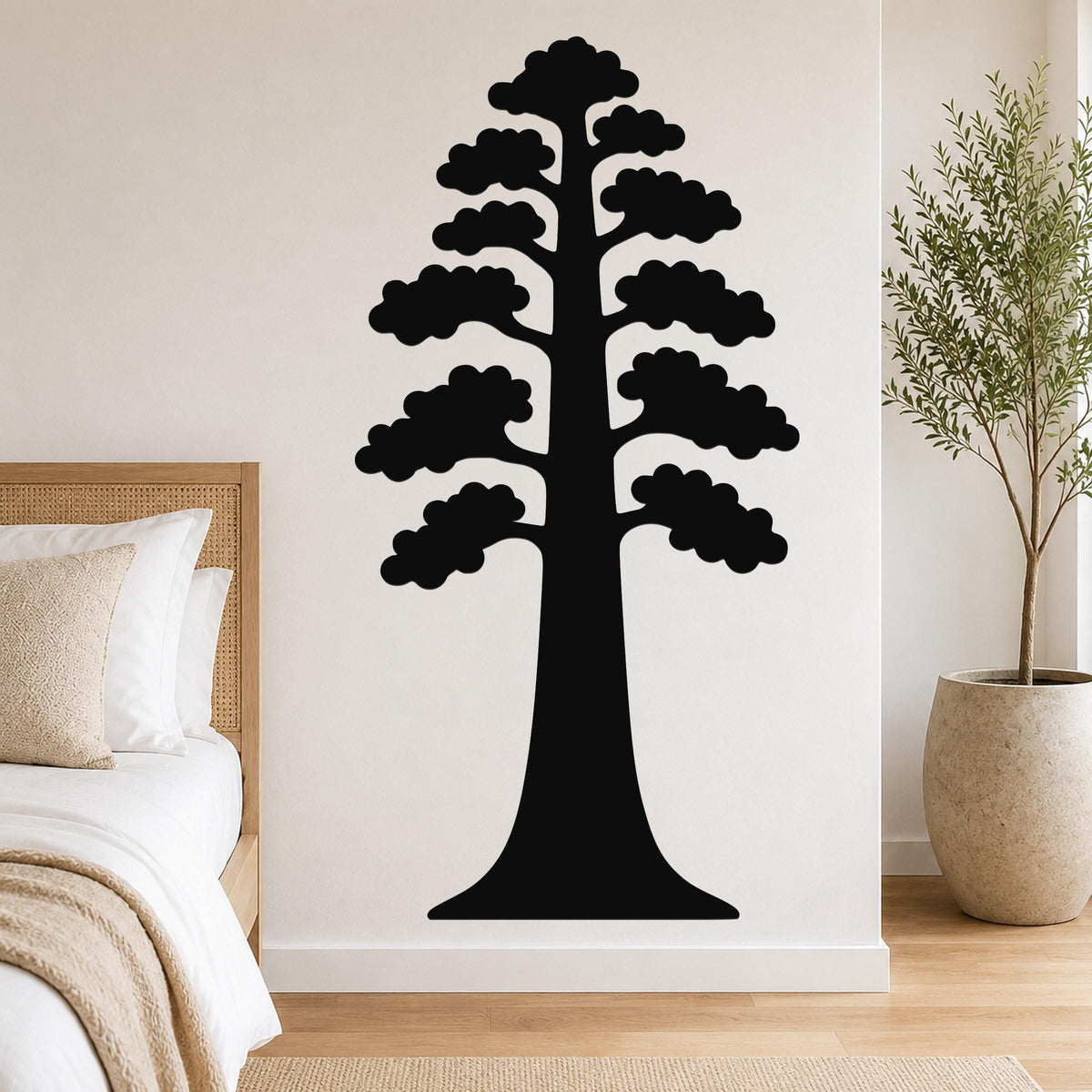 Black metal wall art of a sequoia tree silhouette with layered branches, mounted on a bedroom wall above a bed.