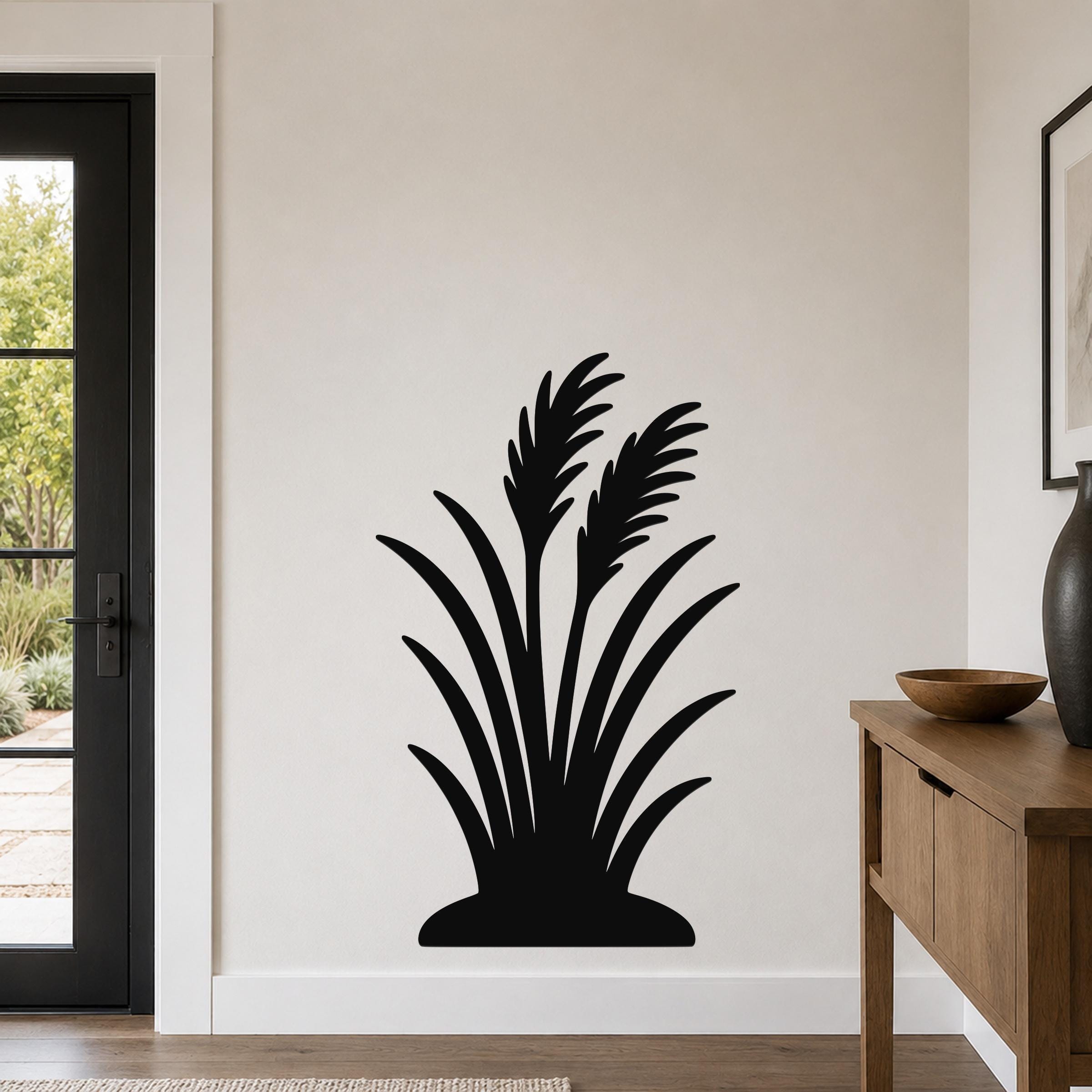 Black metal wall art in a wild grass silhouette design, mounted on a light-colored wall in a modern entryway.