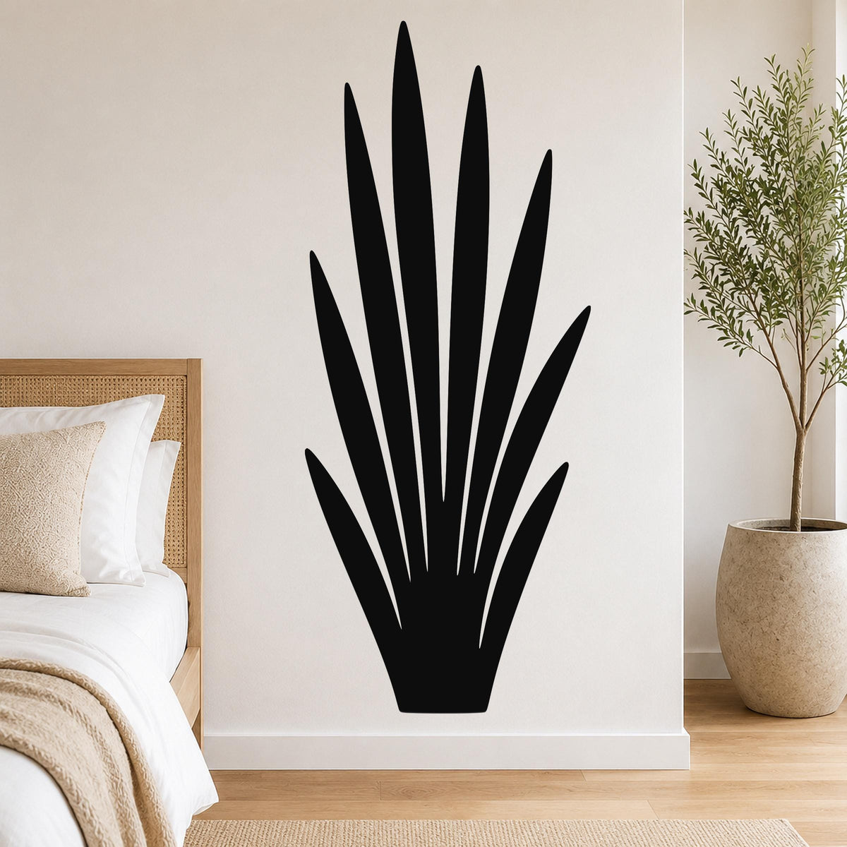 Black metal wall art in a tall, spiky plant silhouette, mounted on a white bedroom wall above a bed.