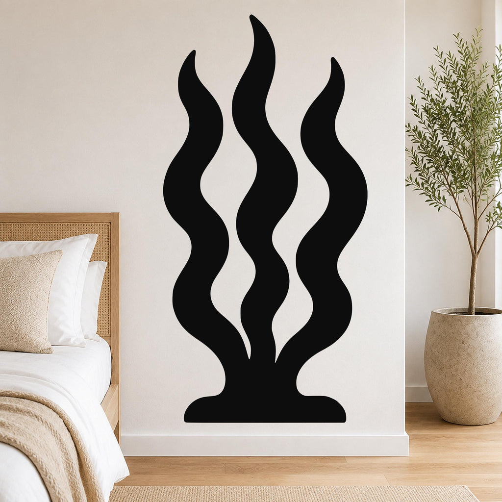 Black metal wall art with three wavy, seaweed-like cutouts, mounted on a bedroom wall above a bed.