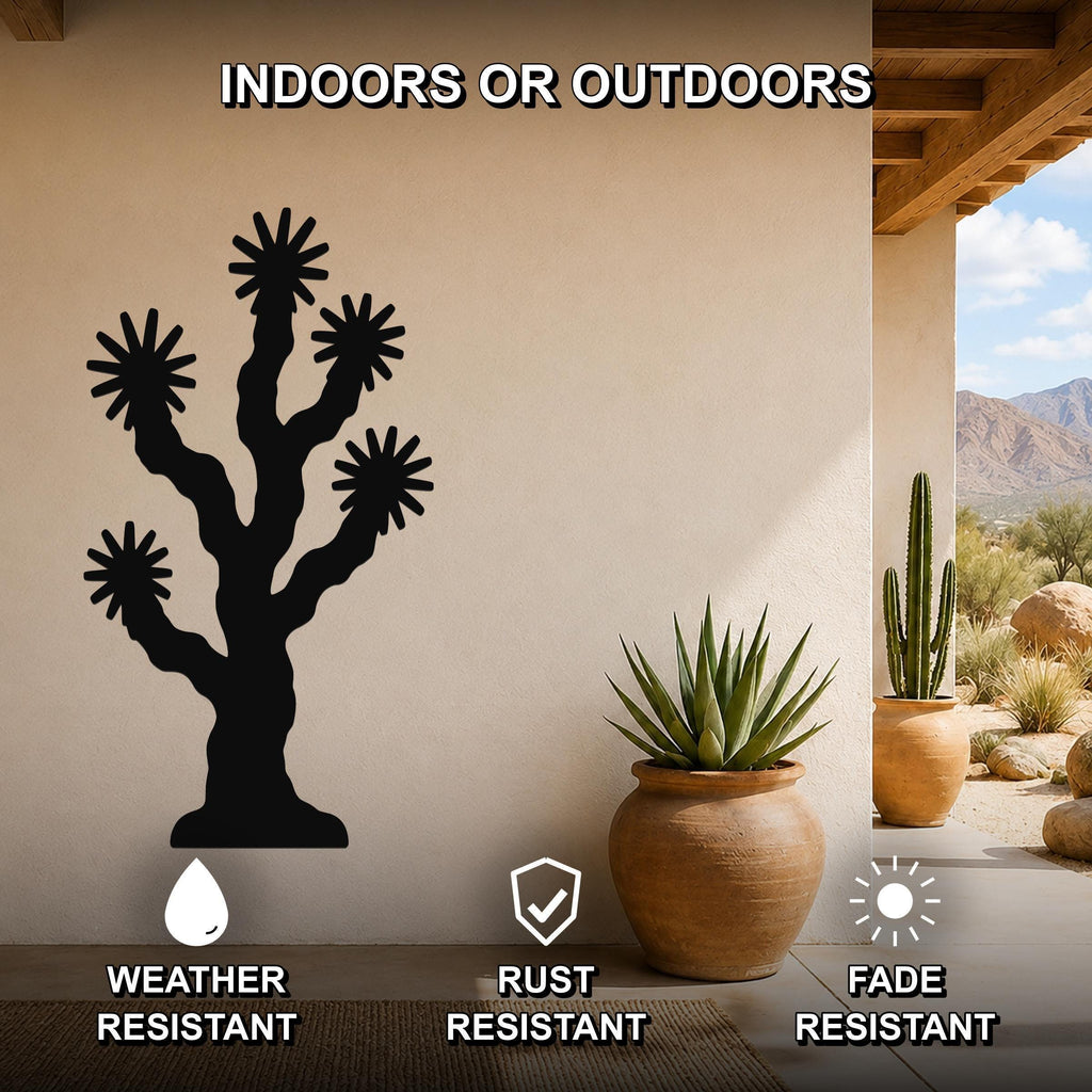 Black metal Joshua tree wall art with starburst cutouts, mounted on a beige outdoor wall above a potted succulent on a patio.