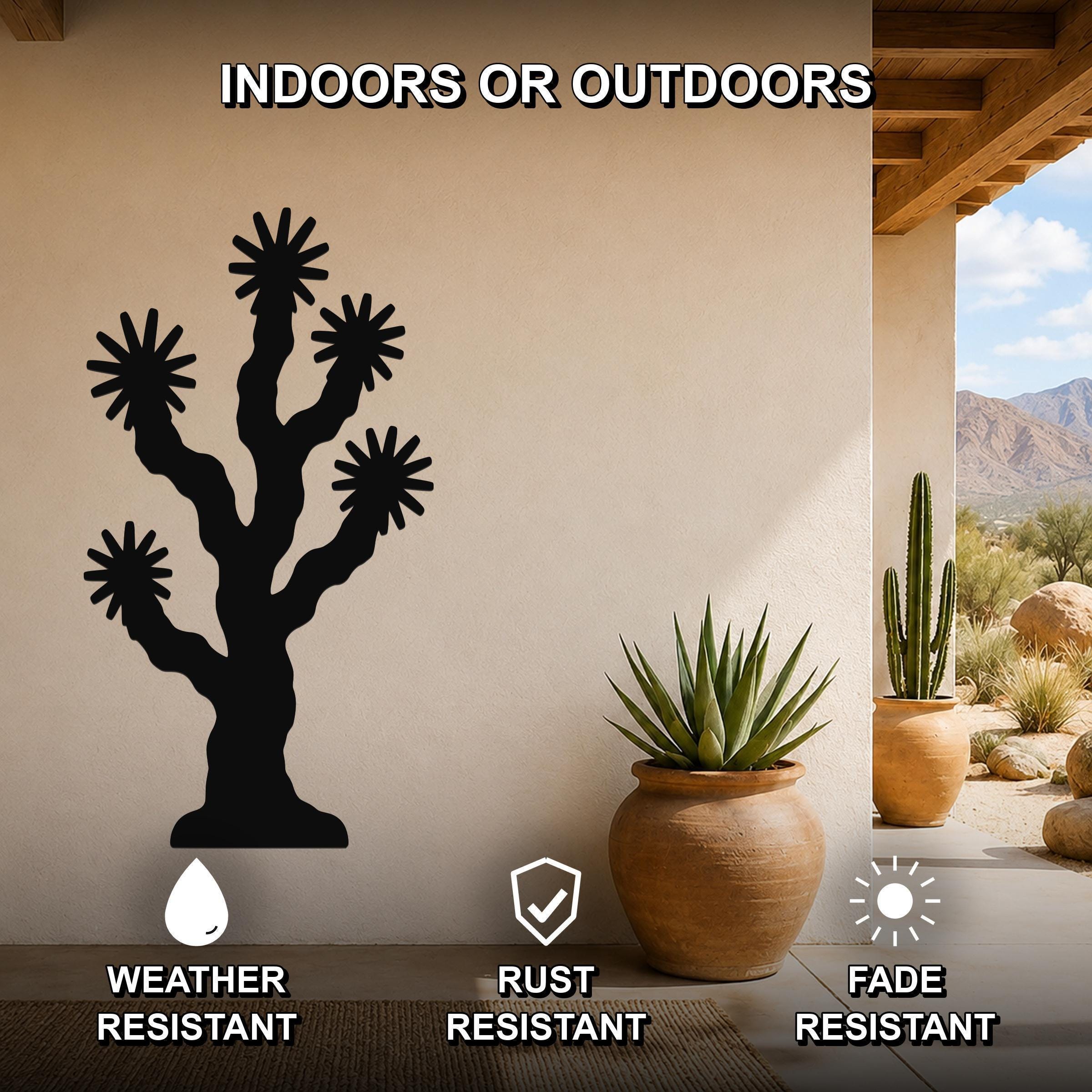 Black metal Joshua tree wall art with starburst cutouts, mounted on a beige outdoor wall above a potted succulent on a patio.