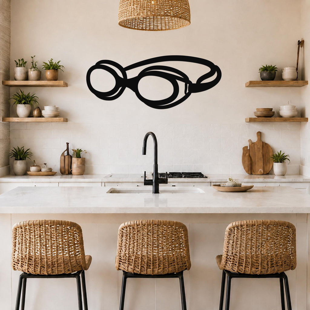 Black metal swim goggles wall art with a bold silhouette design, mounted on a kitchen wall above a counter.