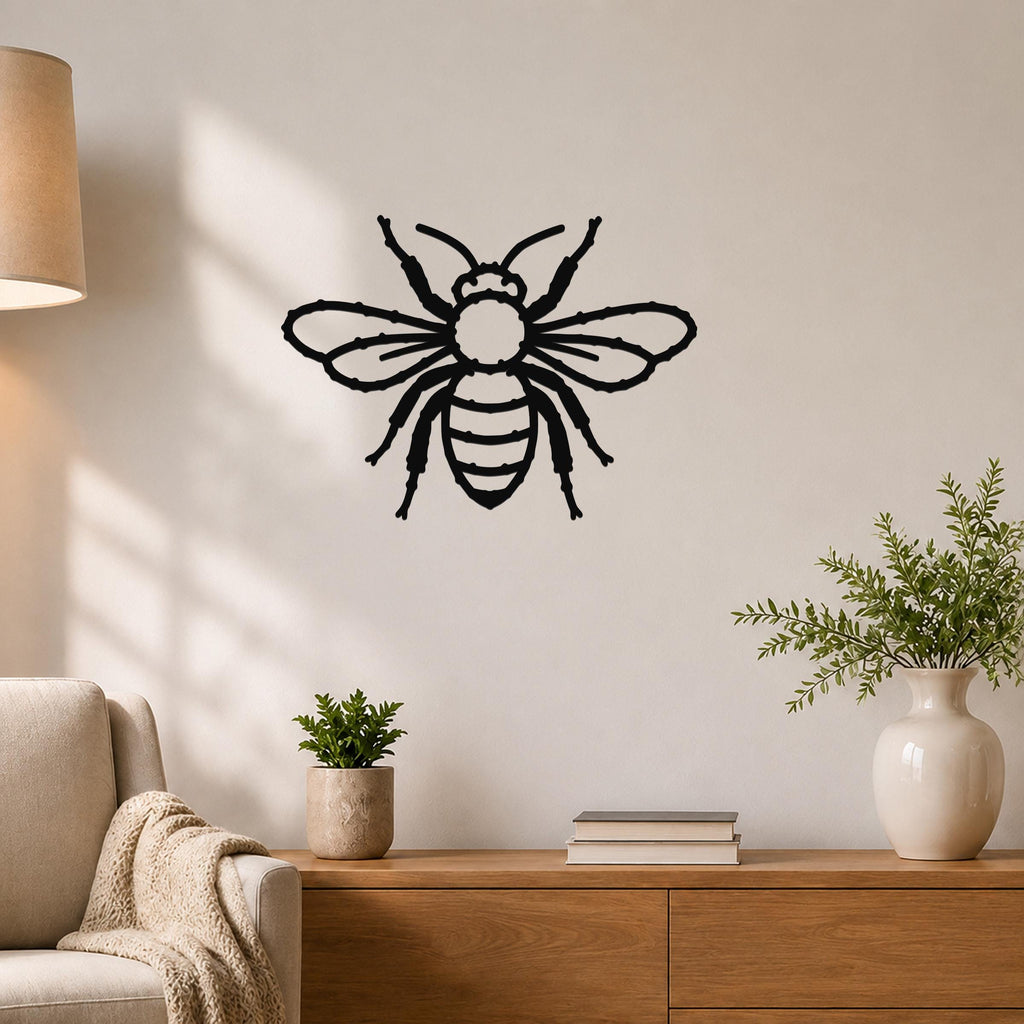 Black metal bee wall art with detailed cutout wings and body, mounted on a light-colored wall above a wooden console in a living room.