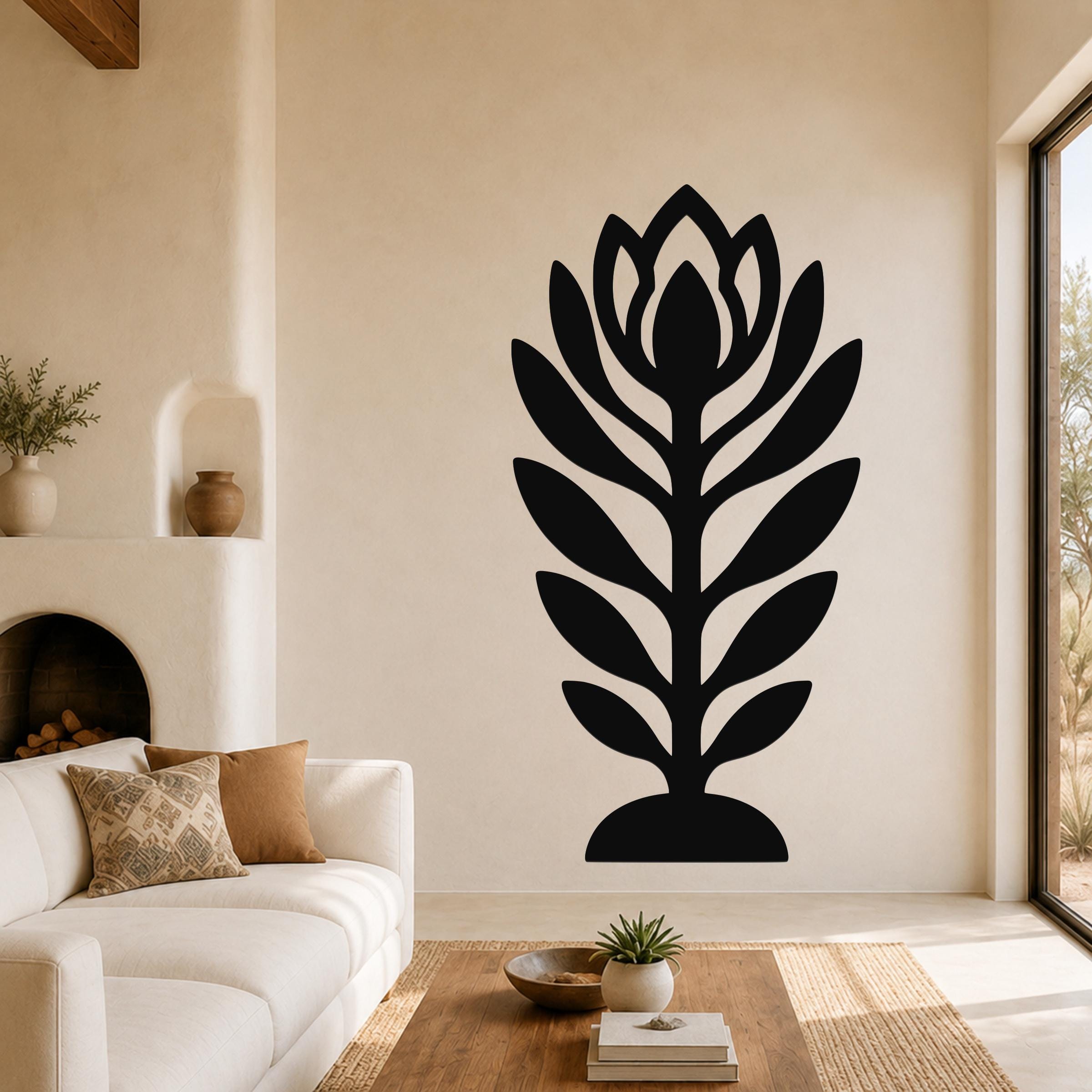 Black metal wall art in a stylized wildflower silhouette with layered petals and leaves, mounted on a living room wall above a sofa.