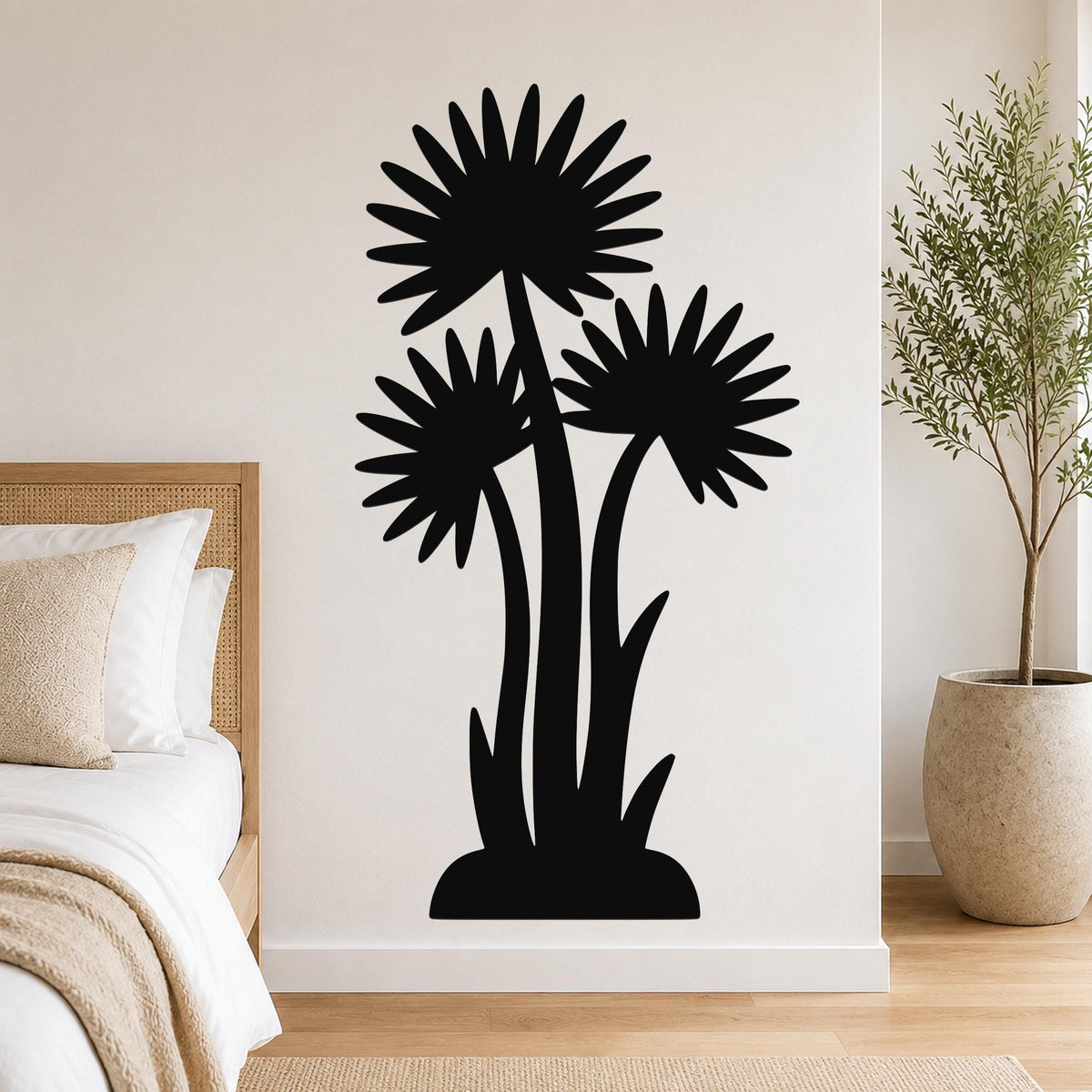 Black metal wall art featuring a silhouette of three palm-like plants with fan-shaped fronds, mounted on a bedroom wall above a bed.