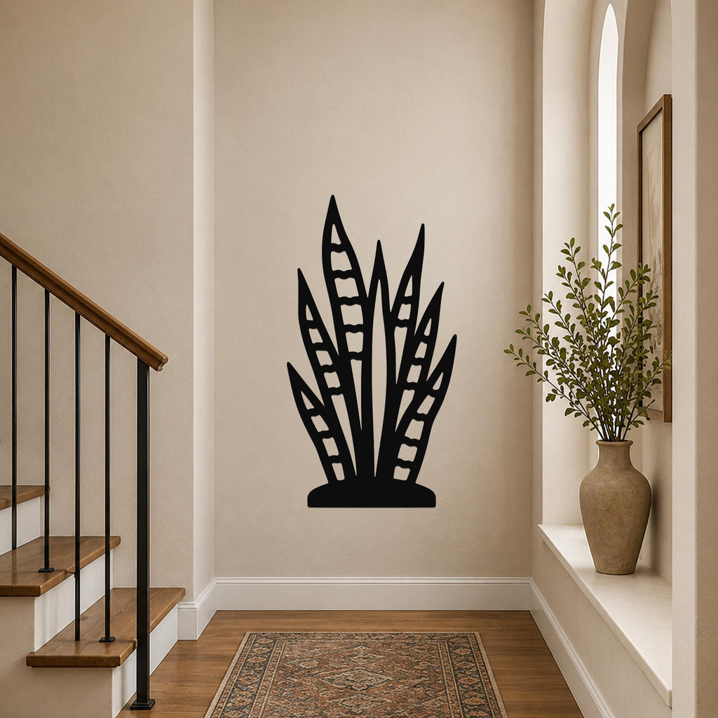 Black metal wall art in a snake plant silhouette with internal leaf cutouts, mounted on a hallway wall above a patterned rug.