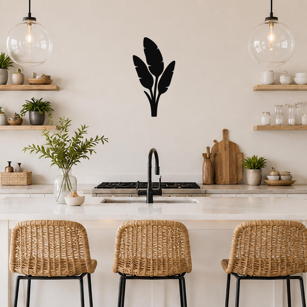 Black metal wall art with a tropical leaf silhouette, mounted on a kitchen wall above a counter with wicker bar stools.