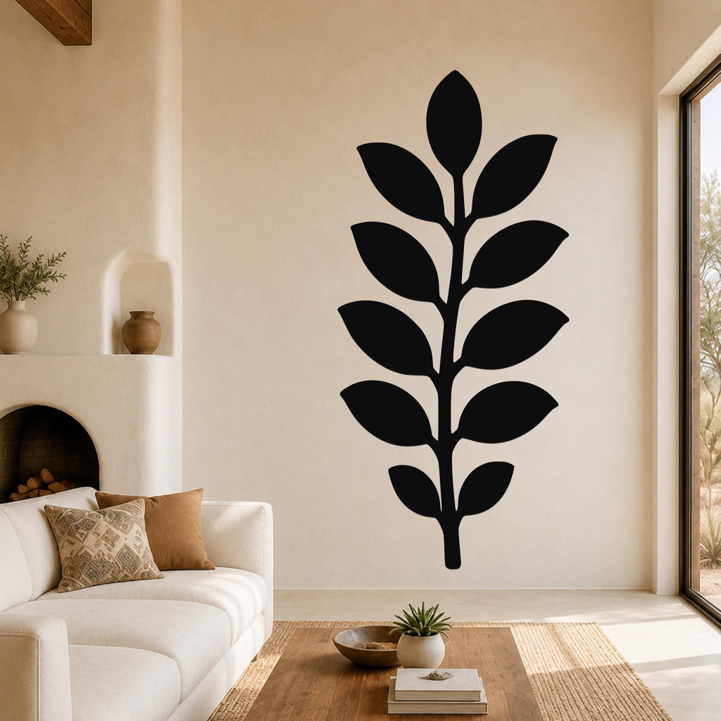 Black metal leaf wall art with a silhouette of a branch and leaves, mounted on a living room wall above a sofa.