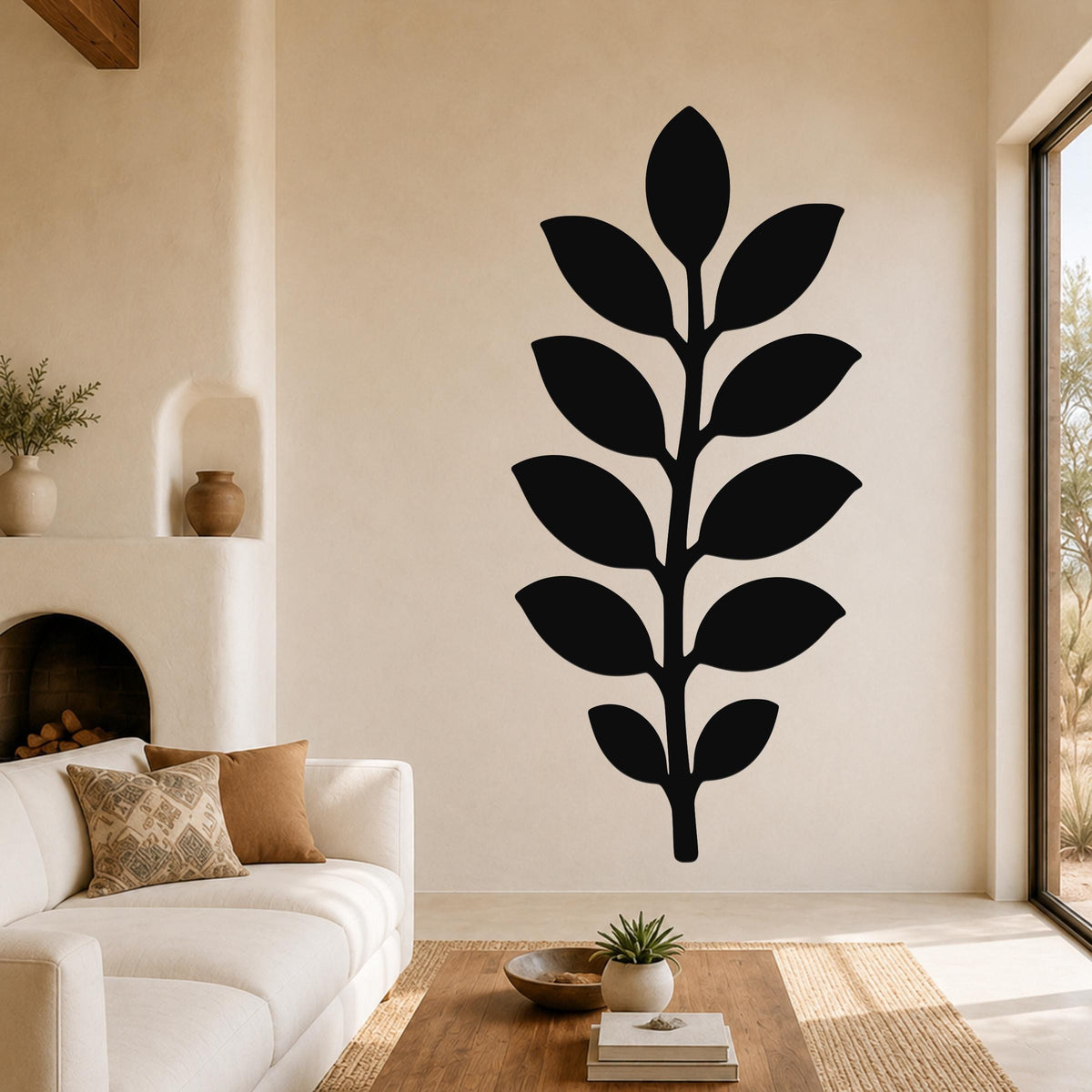 Black metal leaf wall art with a silhouette of a branch and leaves, mounted on a living room wall above a sofa.