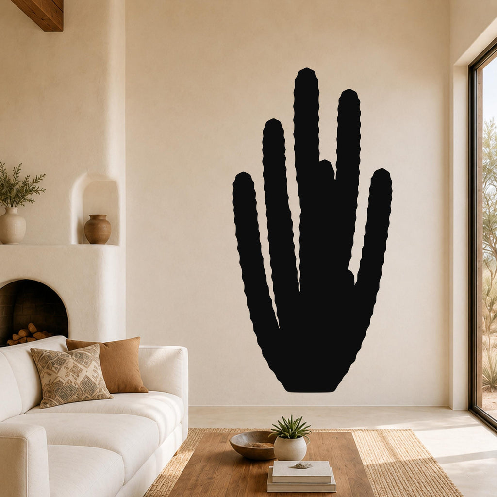 Black metal wall art in the silhouette of an organ pipe cactus with vertical ridges, mounted on a living room wall above a white sofa.