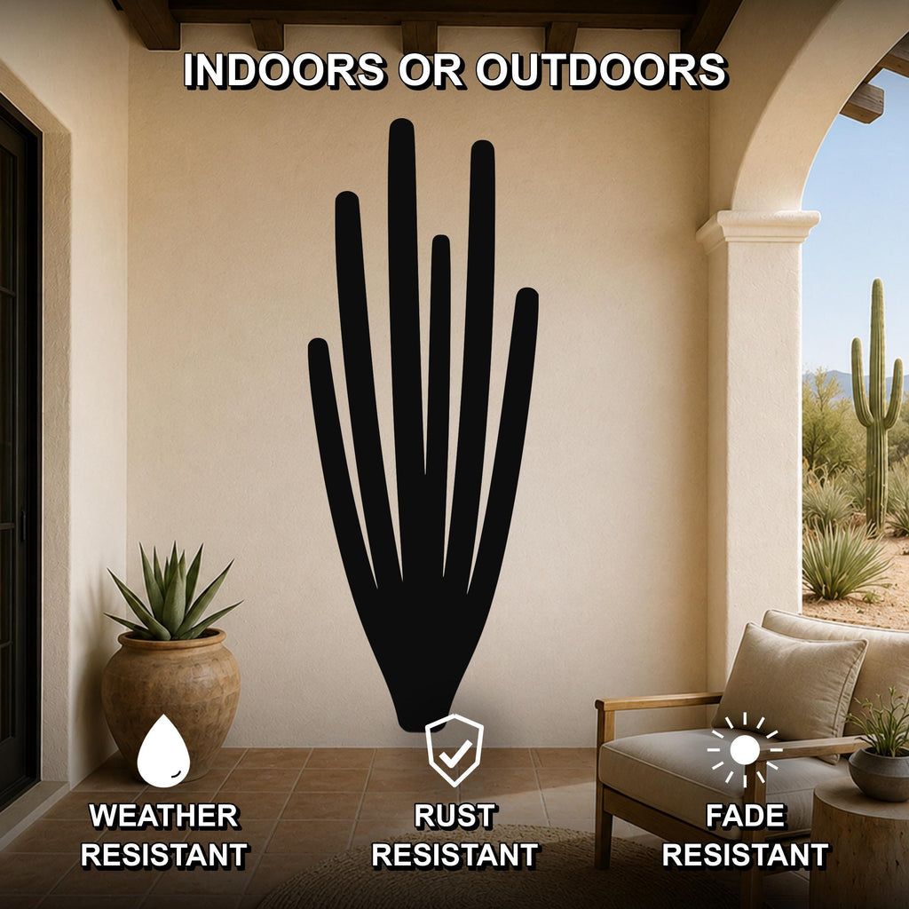 Black metal organ pipe cactus wall art with vertical spine cutouts, mounted on a beige patio wall above a wooden chair in an outdoor living space.