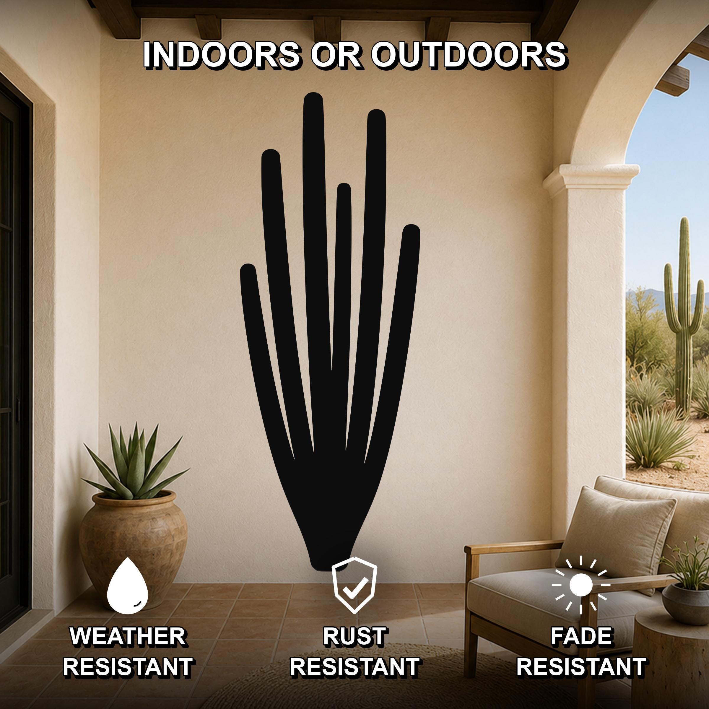 Black metal organ pipe cactus wall art with vertical spine cutouts, mounted on a beige patio wall above a wooden chair in an outdoor living space.