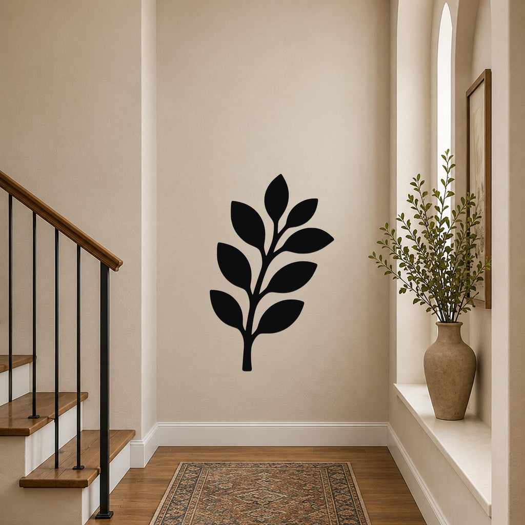 Black metal olive branch wall art with leaf cutouts, mounted on a hallway wall above a patterned rug near a staircase.