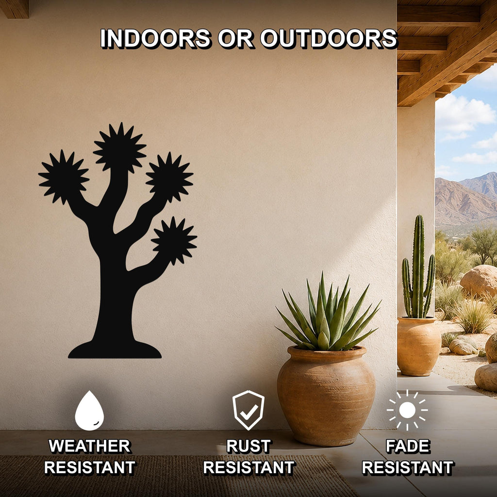 Black metal Joshua tree wall art with starburst cutouts, mounted on a beige outdoor wall above a potted succulent on a patio.