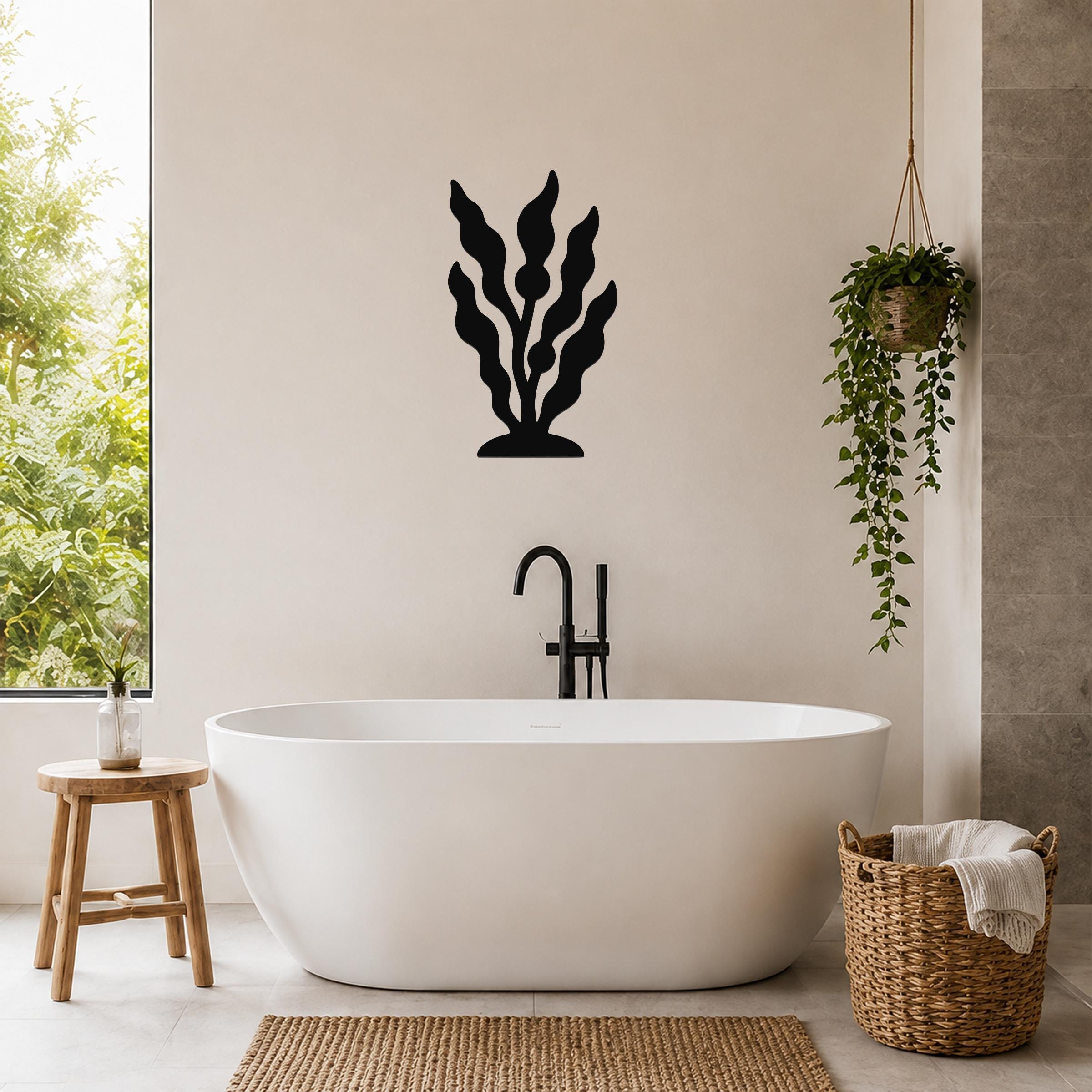 Black metal kelp wall art with leafy cutouts, mounted on a bathroom wall above a freestanding tub.