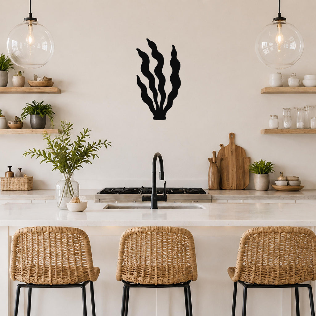 Black metal kelp wall art with wavy blade cutouts, mounted on a kitchen wall above a counter between two glass pendant lights.